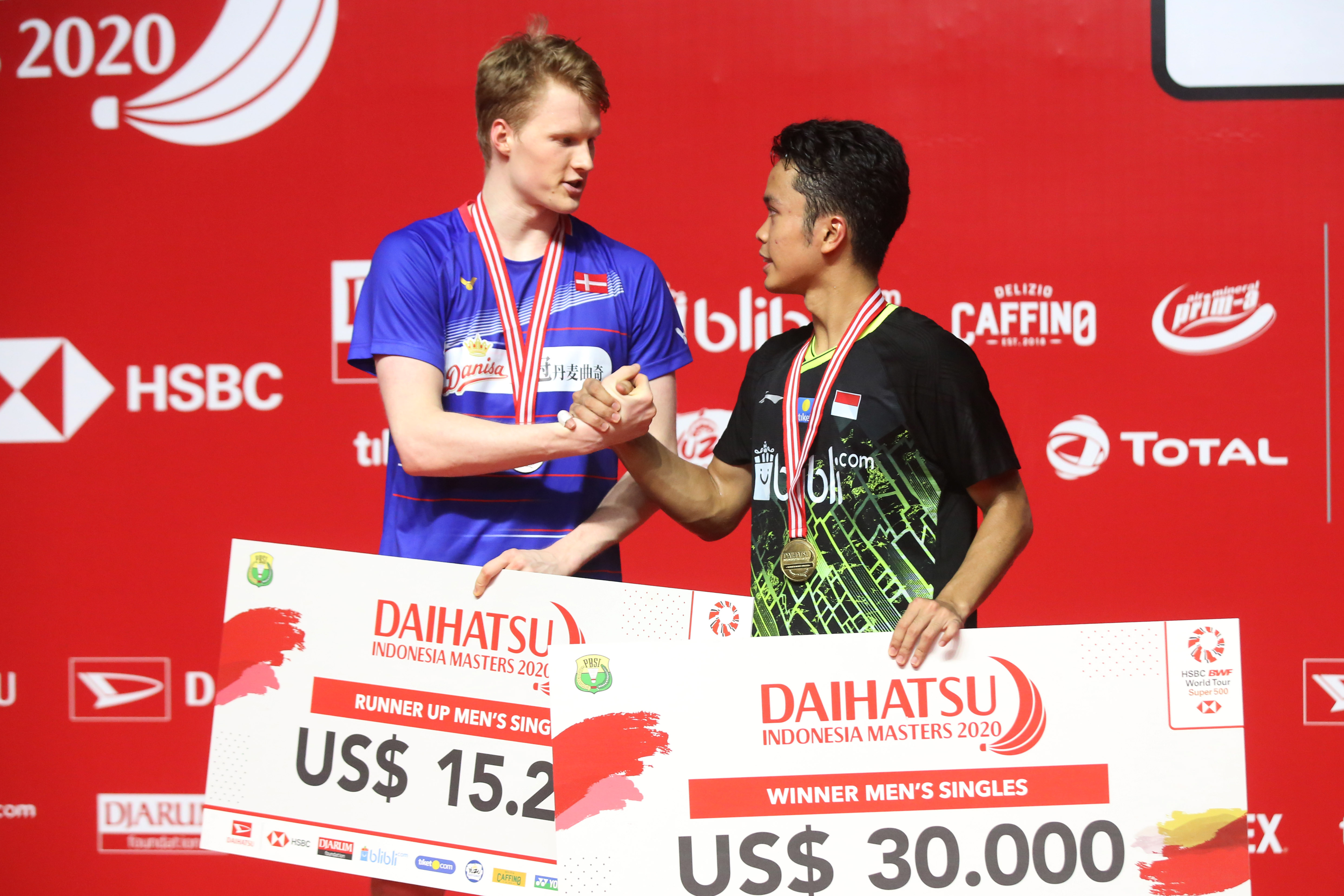 Anthony Sinisuka Ginting bersalaman dengan tunggal putra Denmark Anders Antonsen seusai menerima hadiah