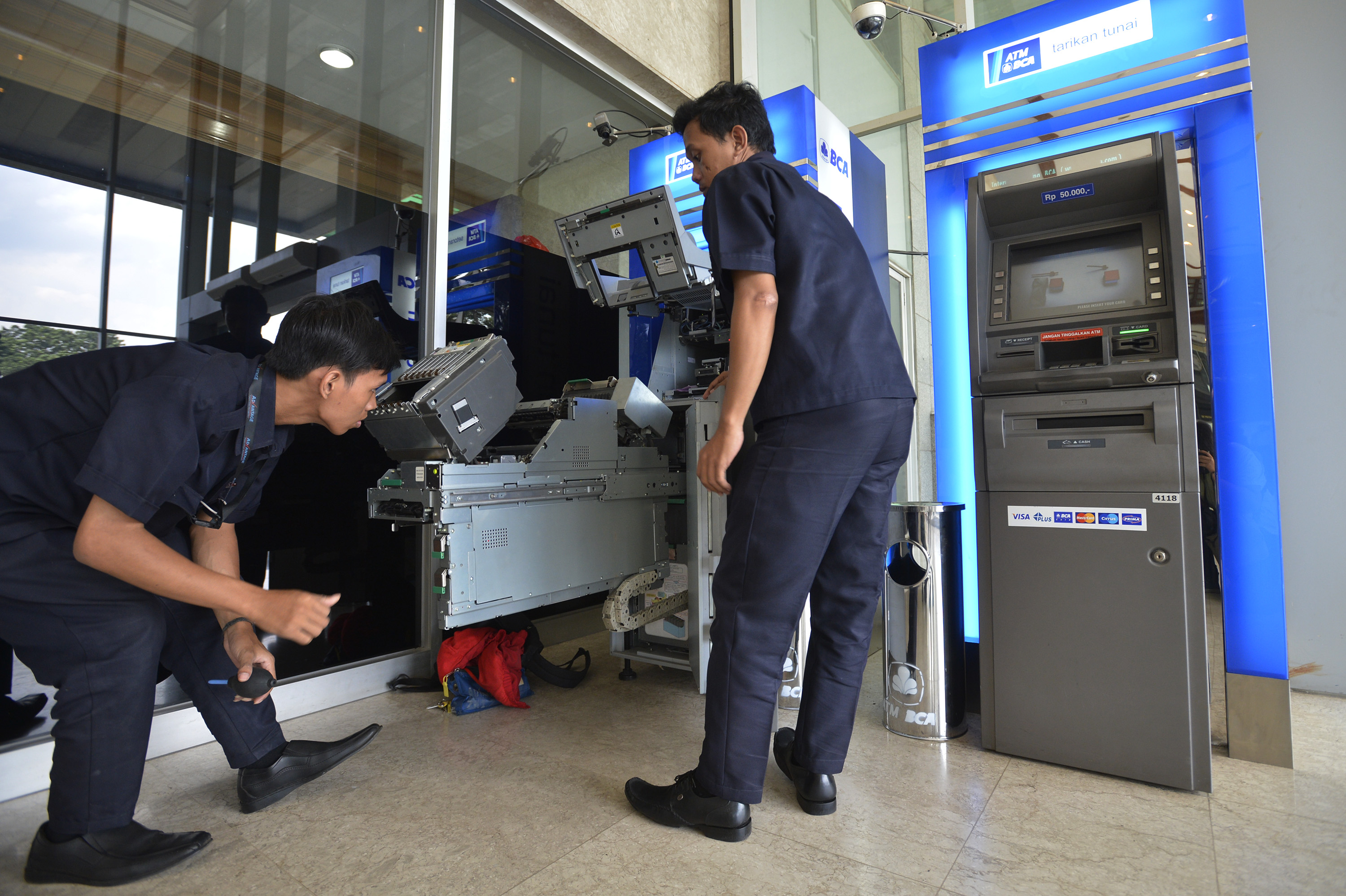 Dua petugas melakukan perawatan pada anjungan tunai mandiri (ATM) BCA di Jakarta, Rabu (4/12)