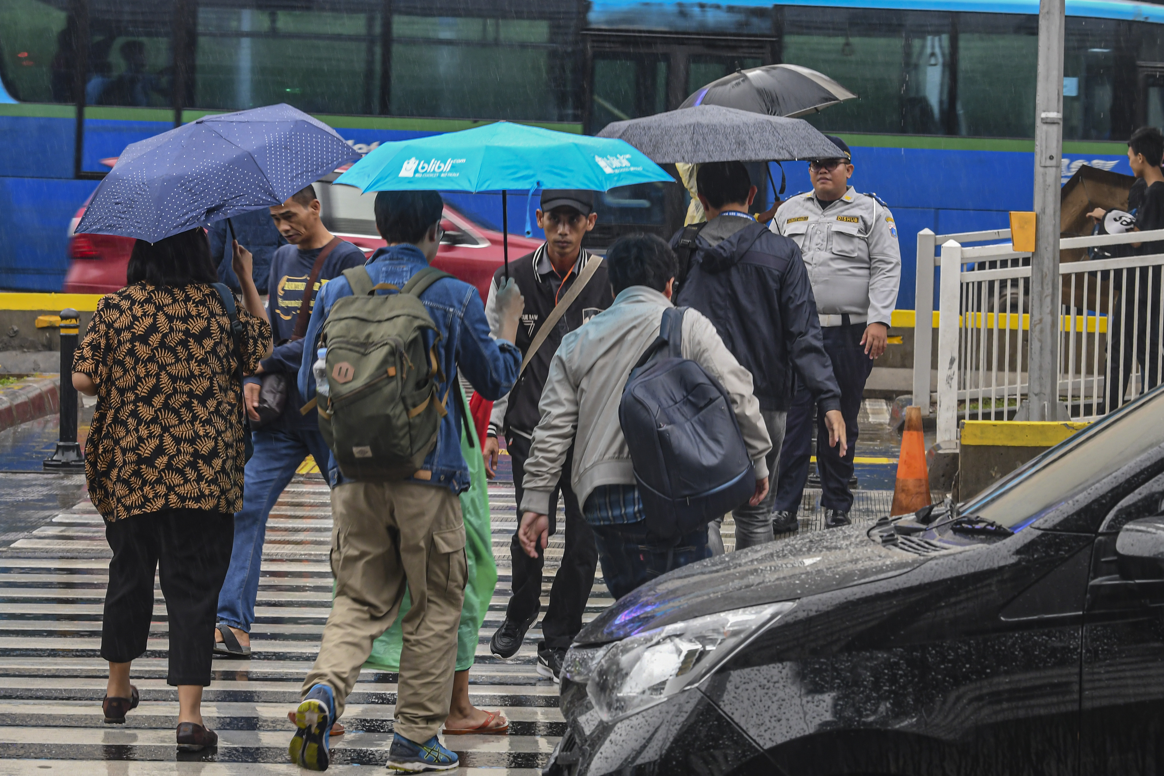 Warga berjalan menggunakan payung saat turun hujan di Jakarta.