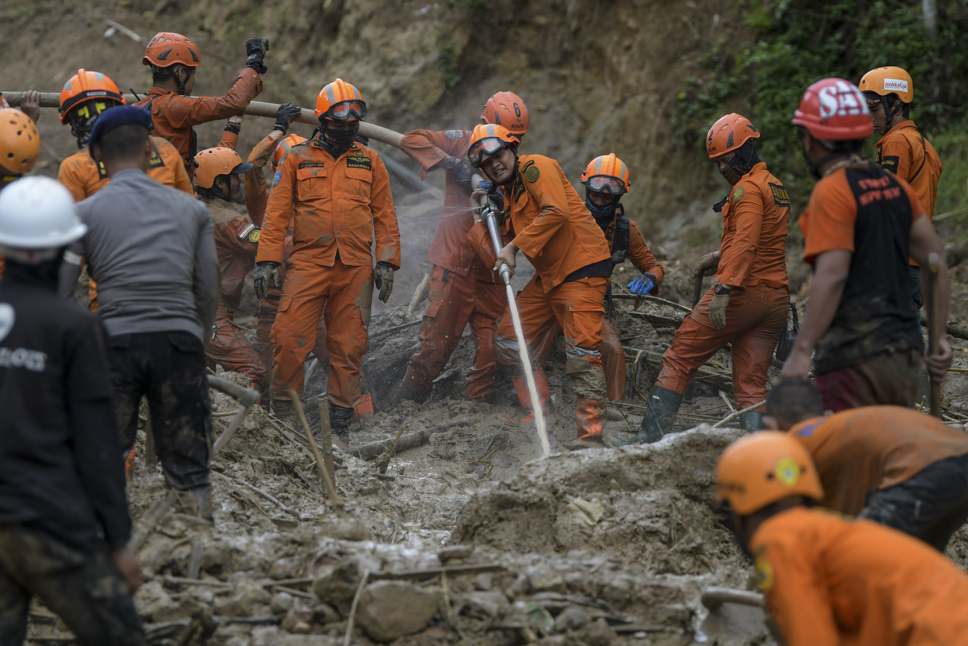 Anggota tim SAR gabungan menggunakan alat penyemprot air untuk melakukan pencarian korban tanah longsor dan banjir bandang  