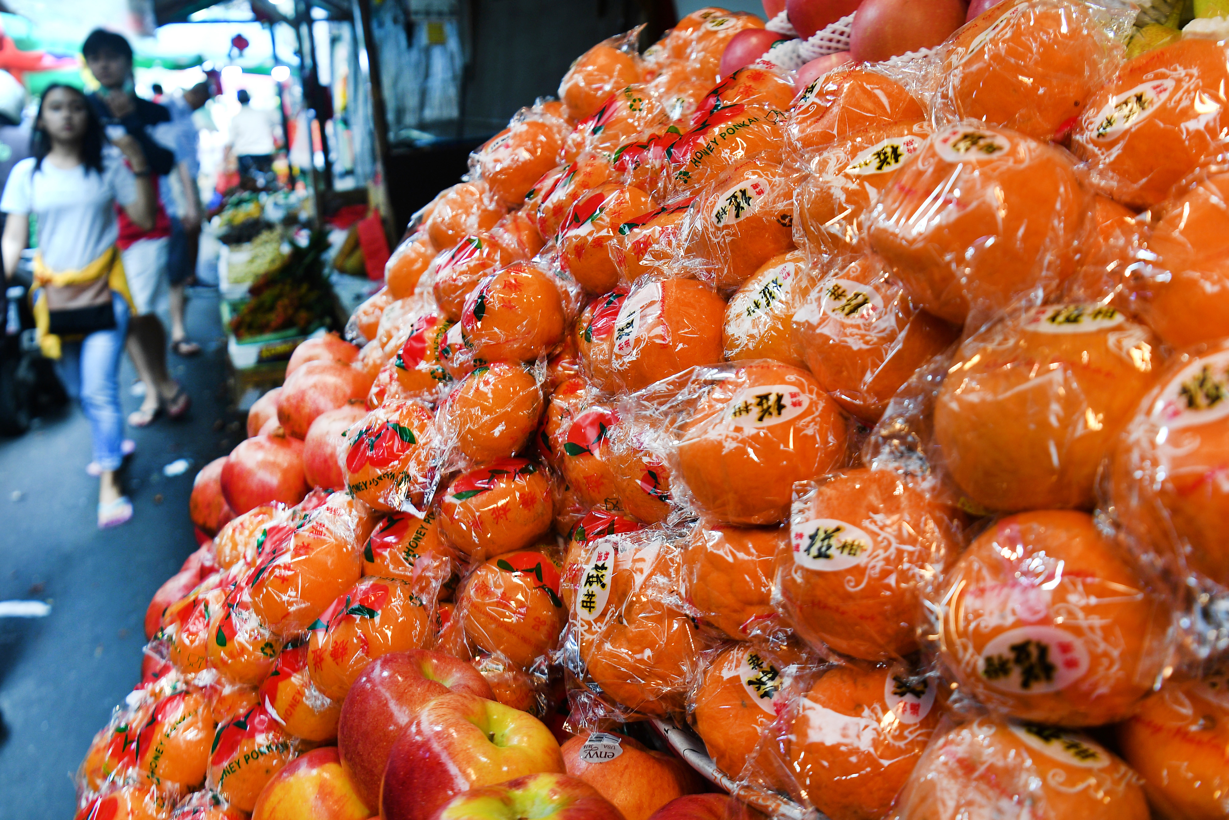Warga melintas di dekat jeruk impor yang dijual di kawasan Glodok, Jakarta Barat, Senin (27/1/2020).