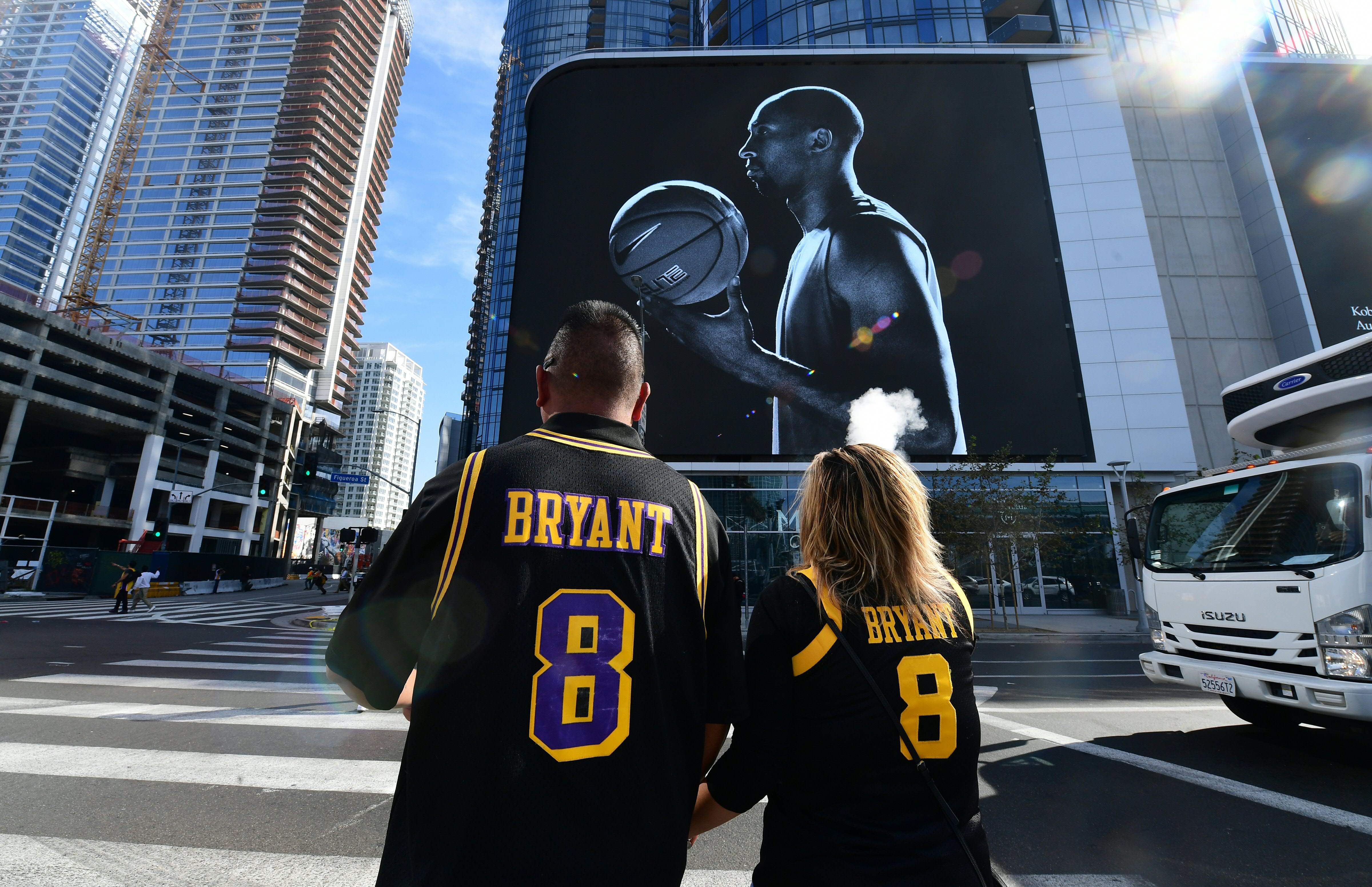 Dua orang mengenakan jersey Los Angeles Lakers mengenakan jersey dengan nama Kobe Bryant di pusat kota Los Angeles.