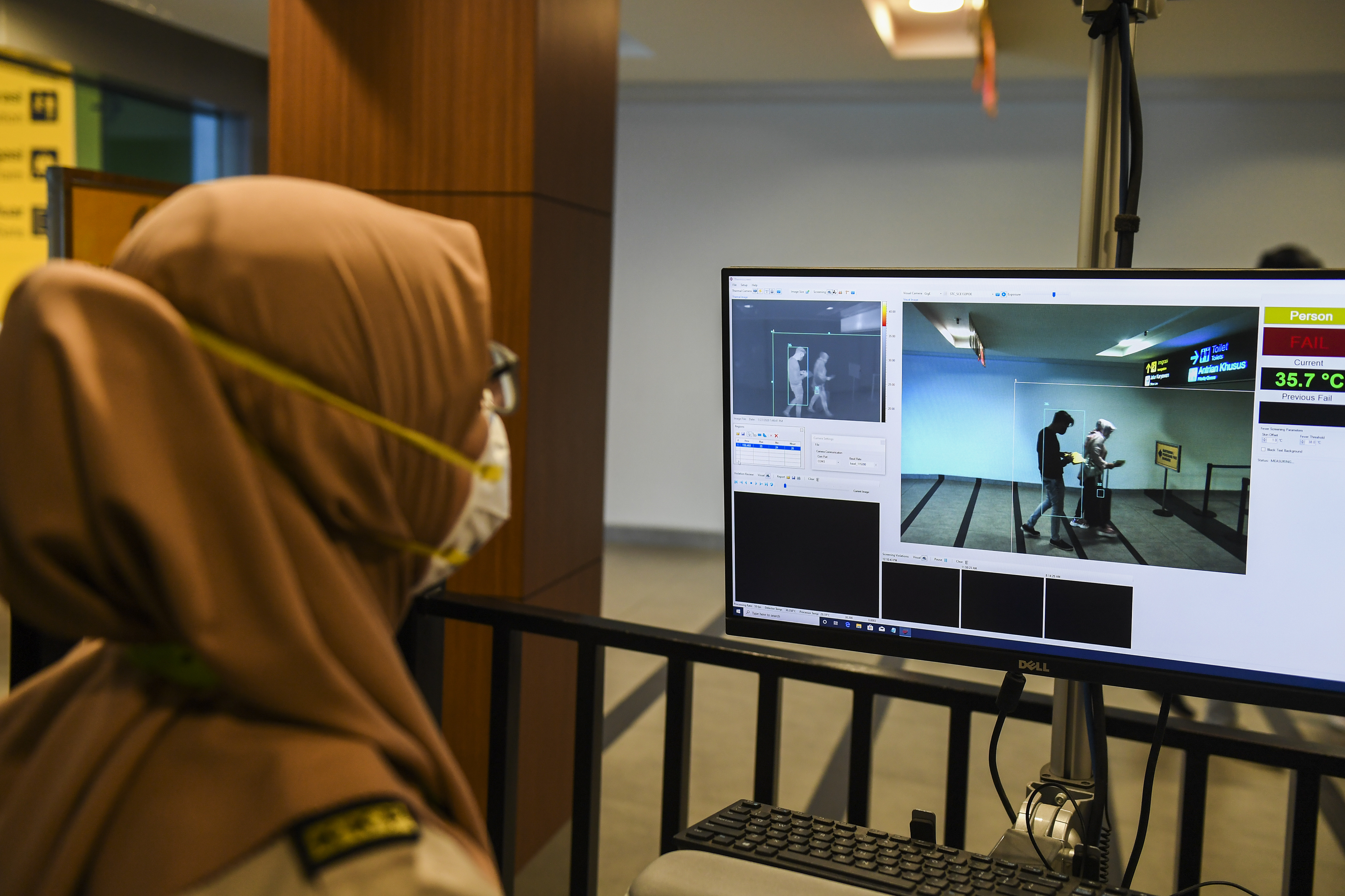  Petugas Kantor Kesehatan Pelabuhan memantau alat deteksi suhu tubuh di terminal kedatangan internasional di Bandara Husein Sastranegara.