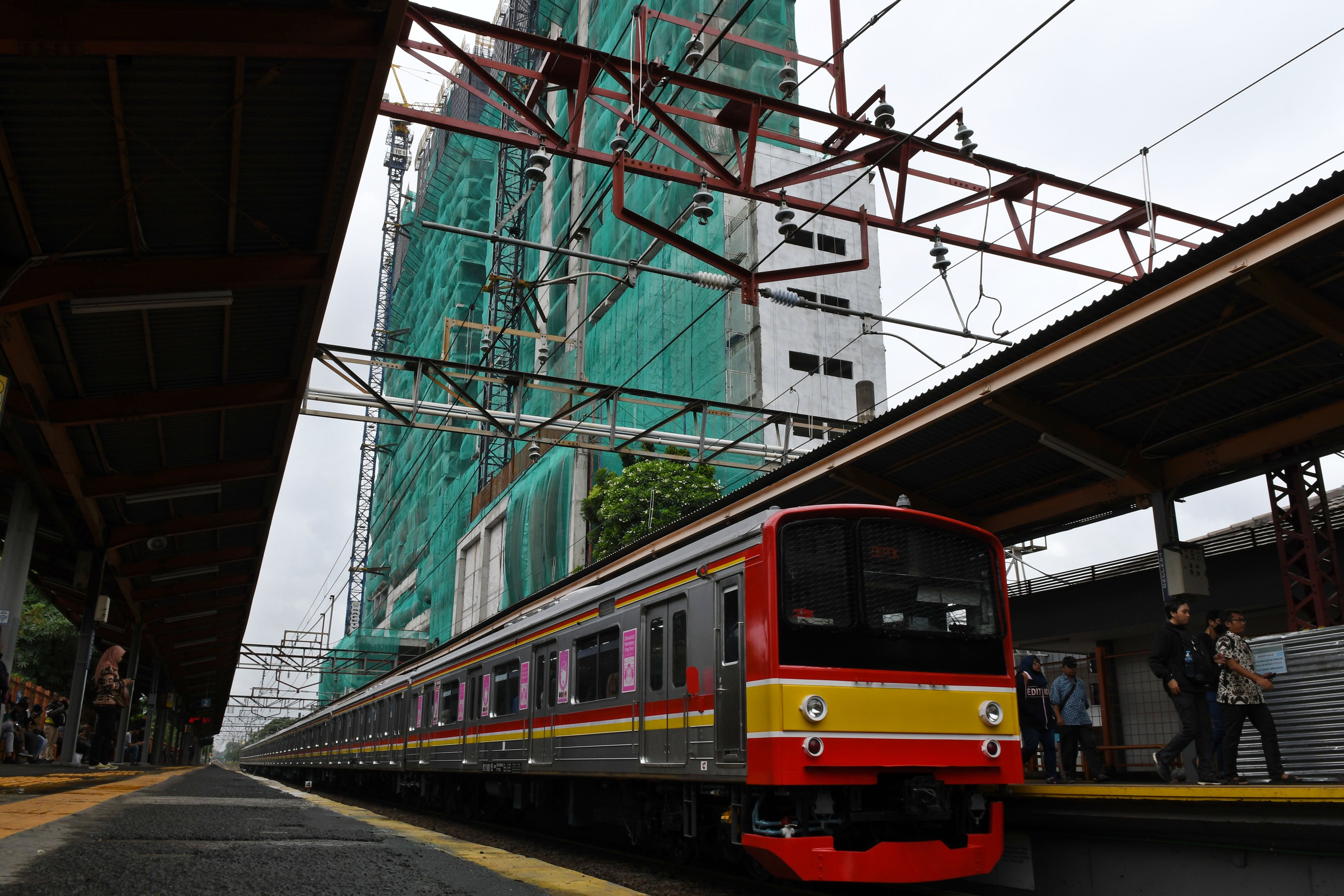 Satu rangkaian KRL Commuterline melintasi pembangunan rumah susun terintegrasi dengan sarana transportasi atau Transit Oriented Development