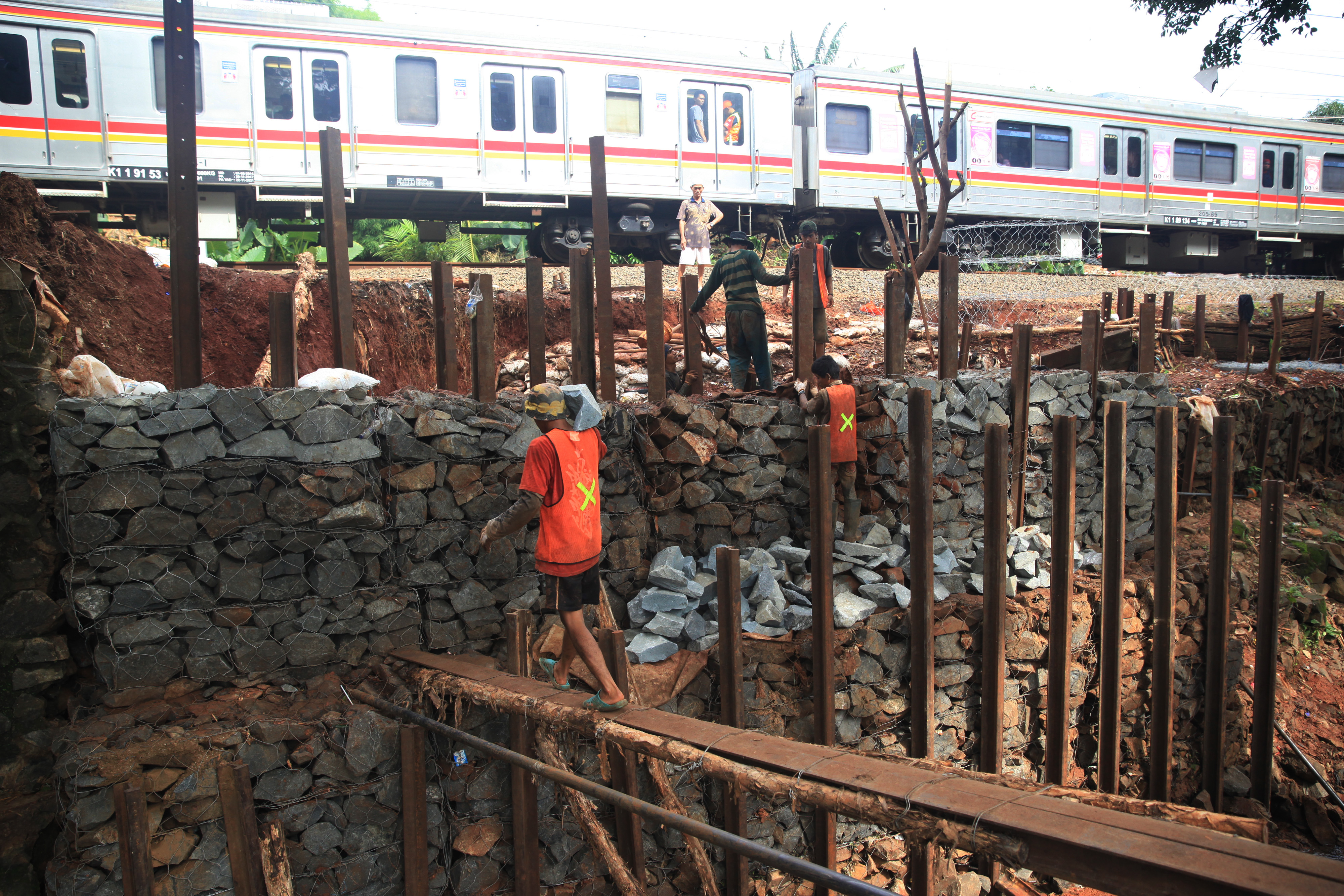 Pekerja membuat tanggul untuk membangun pondasi anti longsor di pinggir rel kereta api, di kawasan Bintaro, Jakarta.