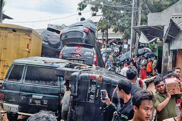 Warga berada di dekat sejumlah mobil yang rusak terdampak banjir di kompleks Perumahan Pondok Gede Permai Bekasi, Jawa Barat, kemarin