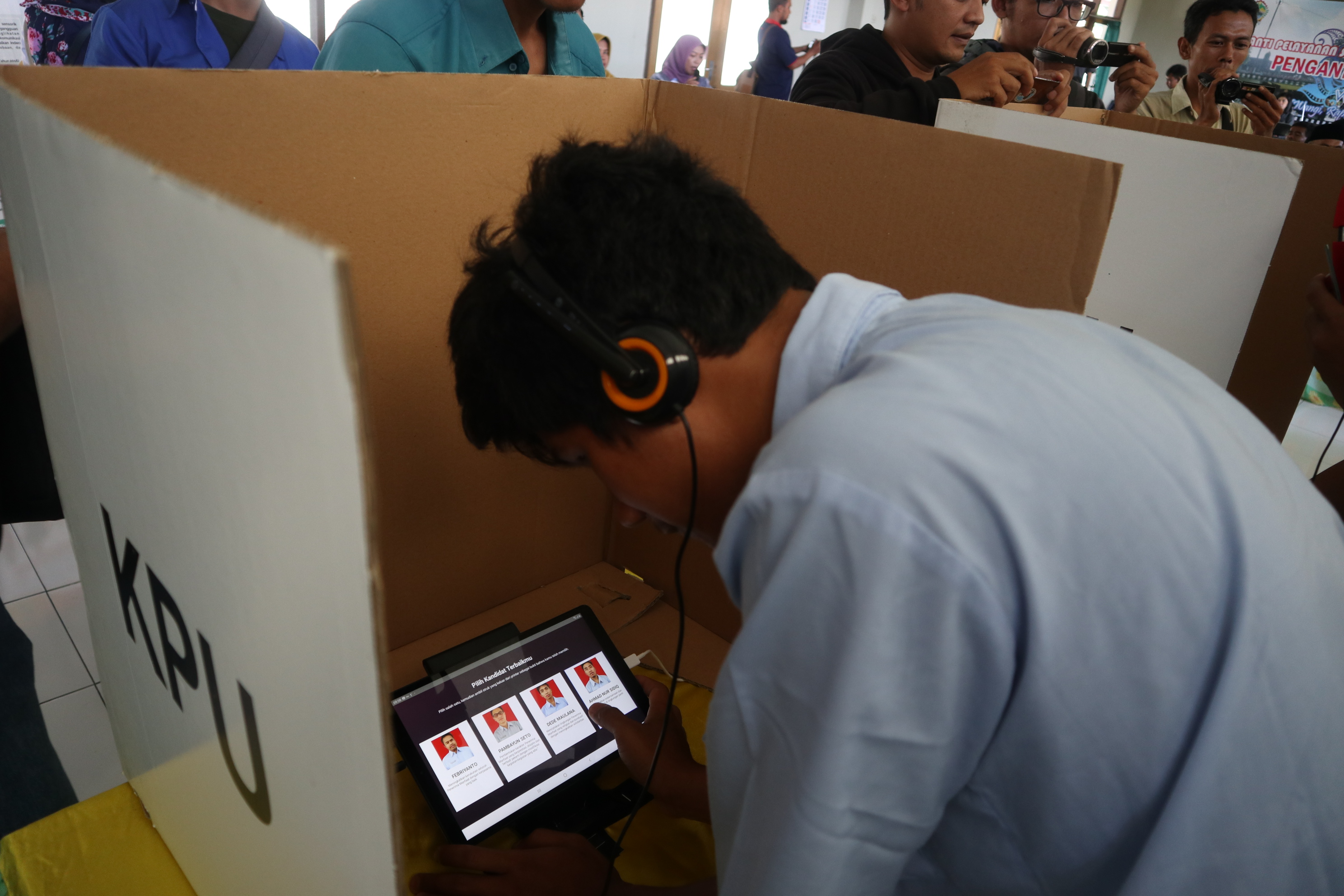 Seorang pengguna  aplikasi e-voting pada smartphone android yang terhubung dengan headseat. Inovasi ini ditawarkan oleh KPU Kab Temanggung. 