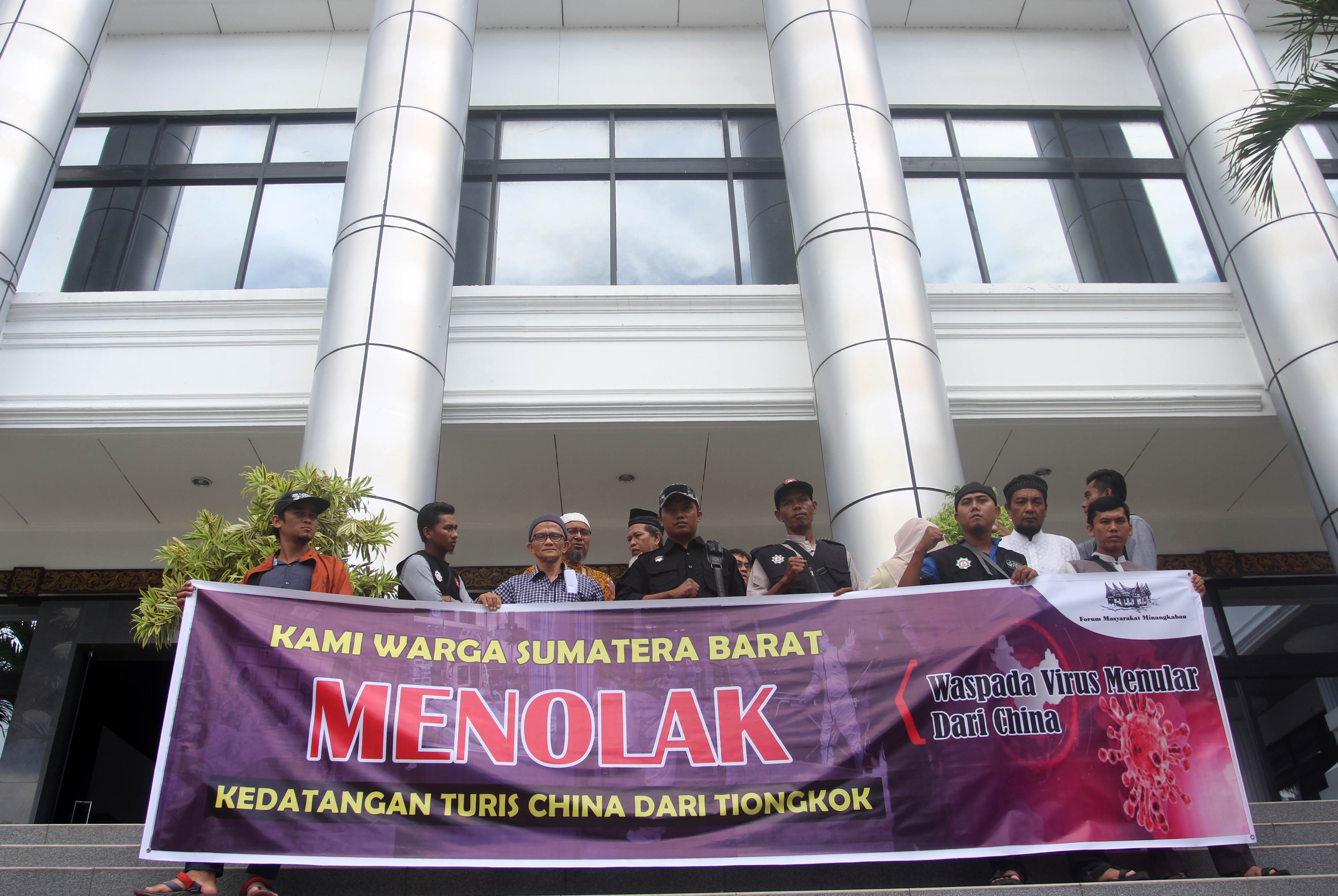 Belasan warga yang tergabung dalam Forum Masyarakat Minangkabau (FMM) menggelar spanduk yang berisikan menolak kedatangan turis China.
