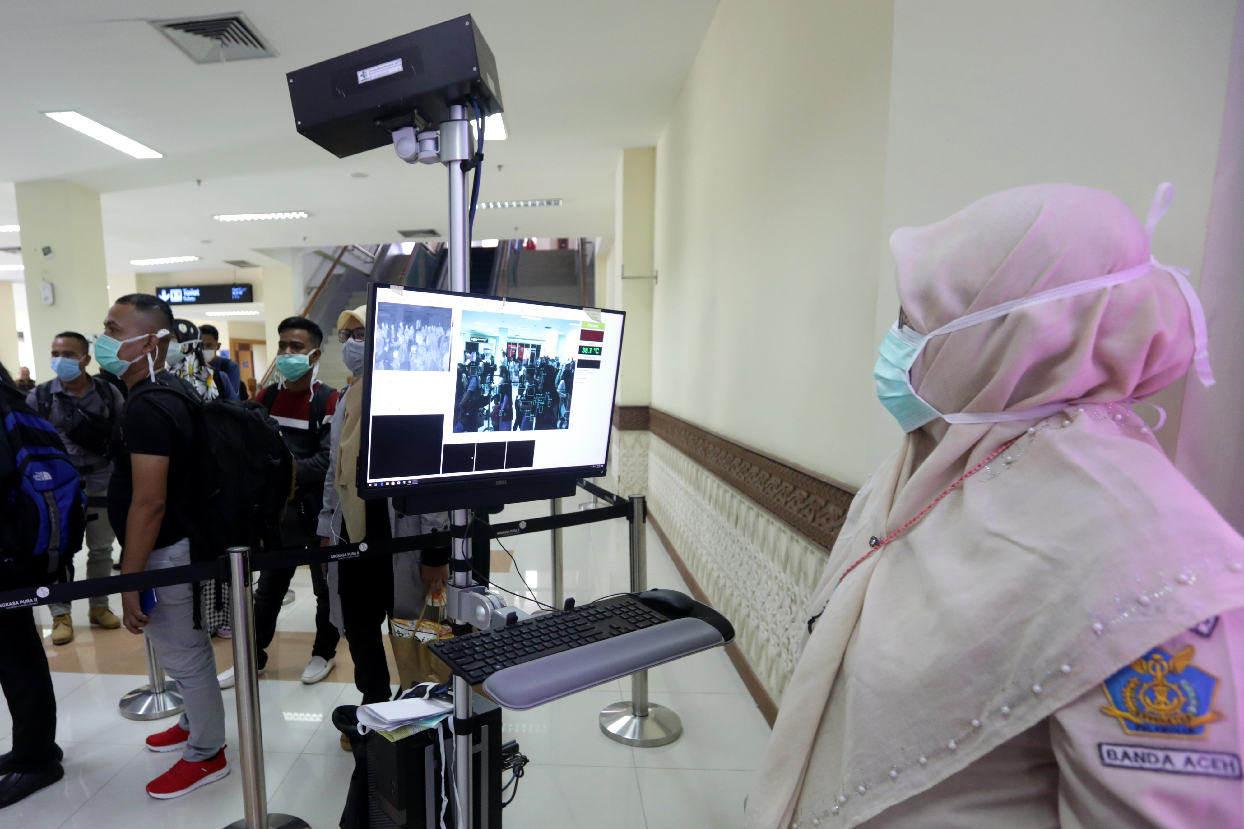  Petugas (kanan) Kantor Kesehatan Pelabuhan (KKP) bandara Sultan Iskandar Muda (SIM) mengamati para penumpang yang baru tiba dari Malaysia