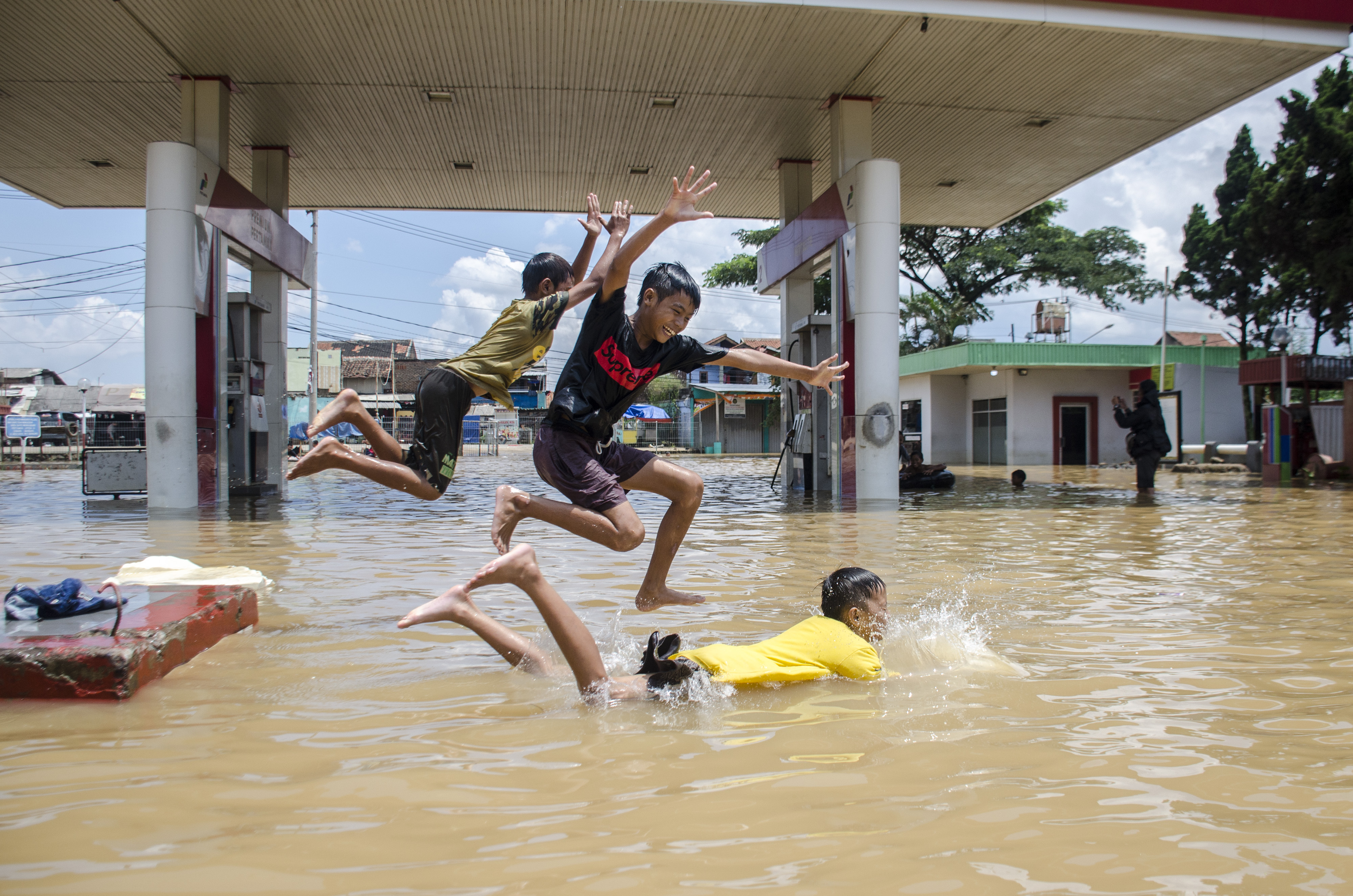 Sejumlah anak bermain di genangan banjir di Jalan Raya Baleendah, Kabupaten Bandung, Jawa Barat.