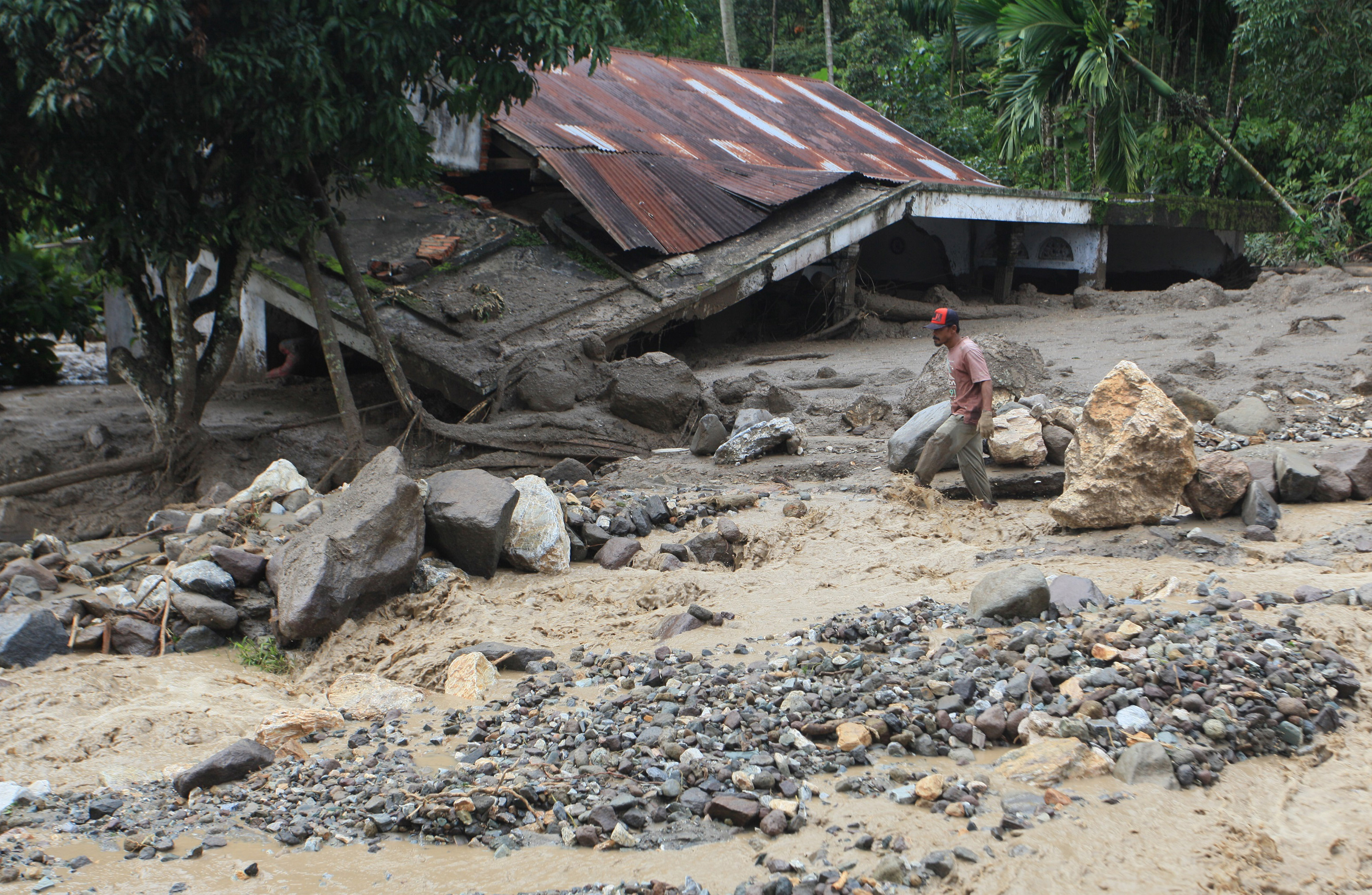 Warga melintas di depan rumah yang ambruk diterjang banjir bandang di Nagari Malalo, Tanah Datar, Sumatra Barat, kemarin.