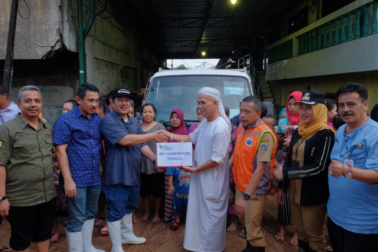 Deputi Direktur BP Jamsostek Wilayah DKI Jakarta, Cotta Sembiring, (tengah) menyerahkan bantuan kepada korban banjir di Grogol, Jakarta... 