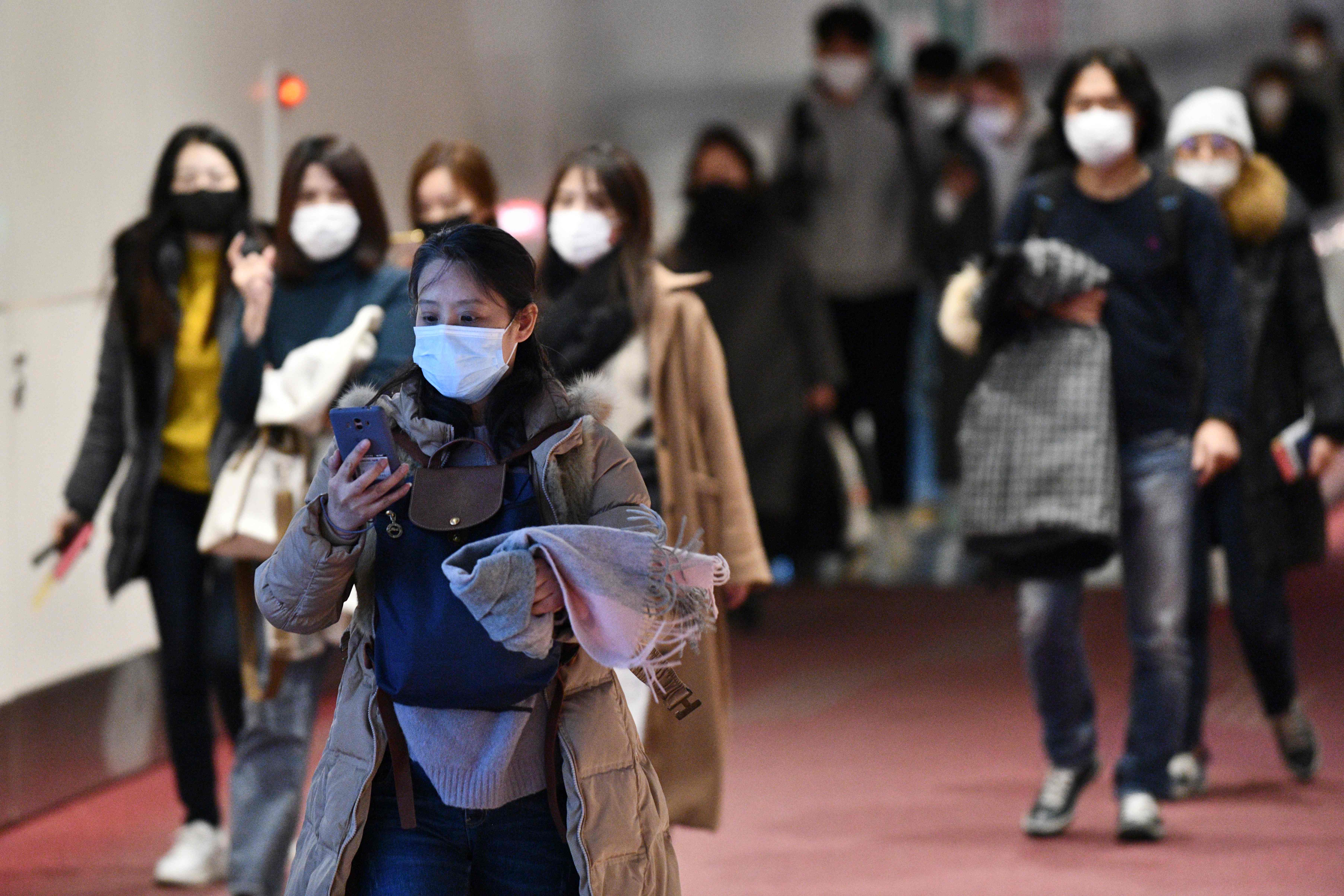 Penumpang dari luar negeri mengenakan masker saat tiba di Bandara Haneda, Tokyo, Jepang
