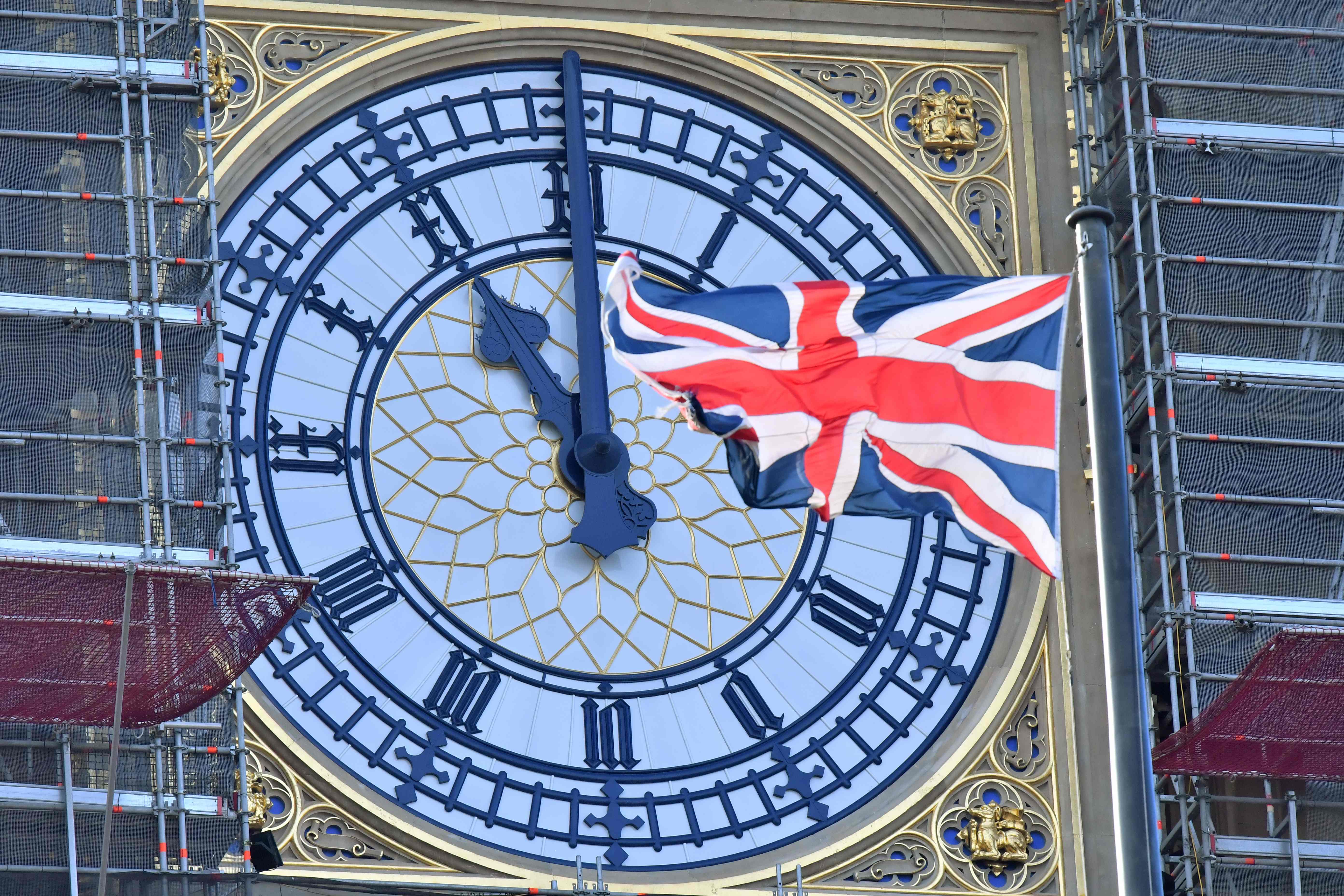 Jam  yang menghadap Menara Elizabeth atau yang dikenal dengan nama Big Ben tampak dengan bendera Inggris.l
