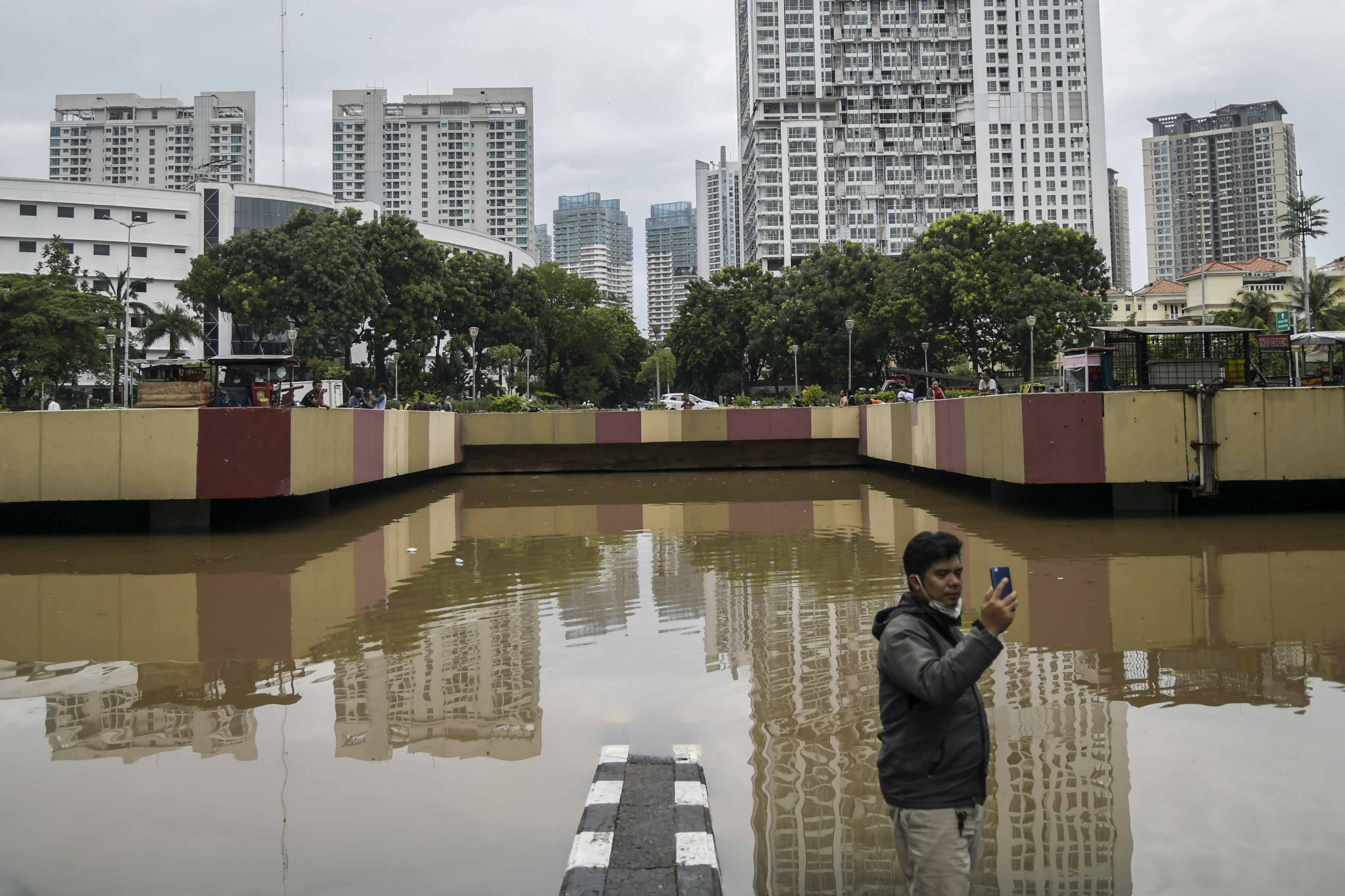 Warga ber swa foto saat banjir menutup underpass kemayoran