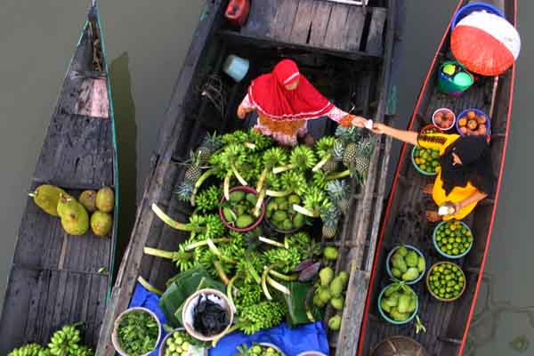Pedagang pasar terapung melakukan transaksi di atas sungai Martapura, desa Lok Baintan, Kabupaten Banjar, Kalimantan Selatan.