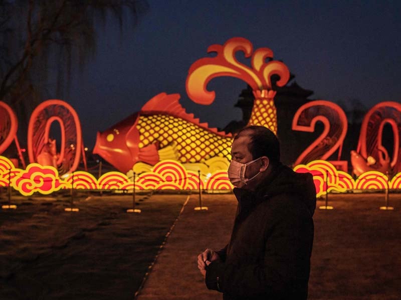 Seorang pria melintas dengan menggunakan masker di kota Wuhan, Tiongkok.