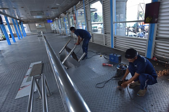 Petugas sarana dan prasarana Trans-Jakarta memasang kursi tunggu penumpang di Halte Transjakarta Kampung Melayu, Jakarta, Jumat (26/5).