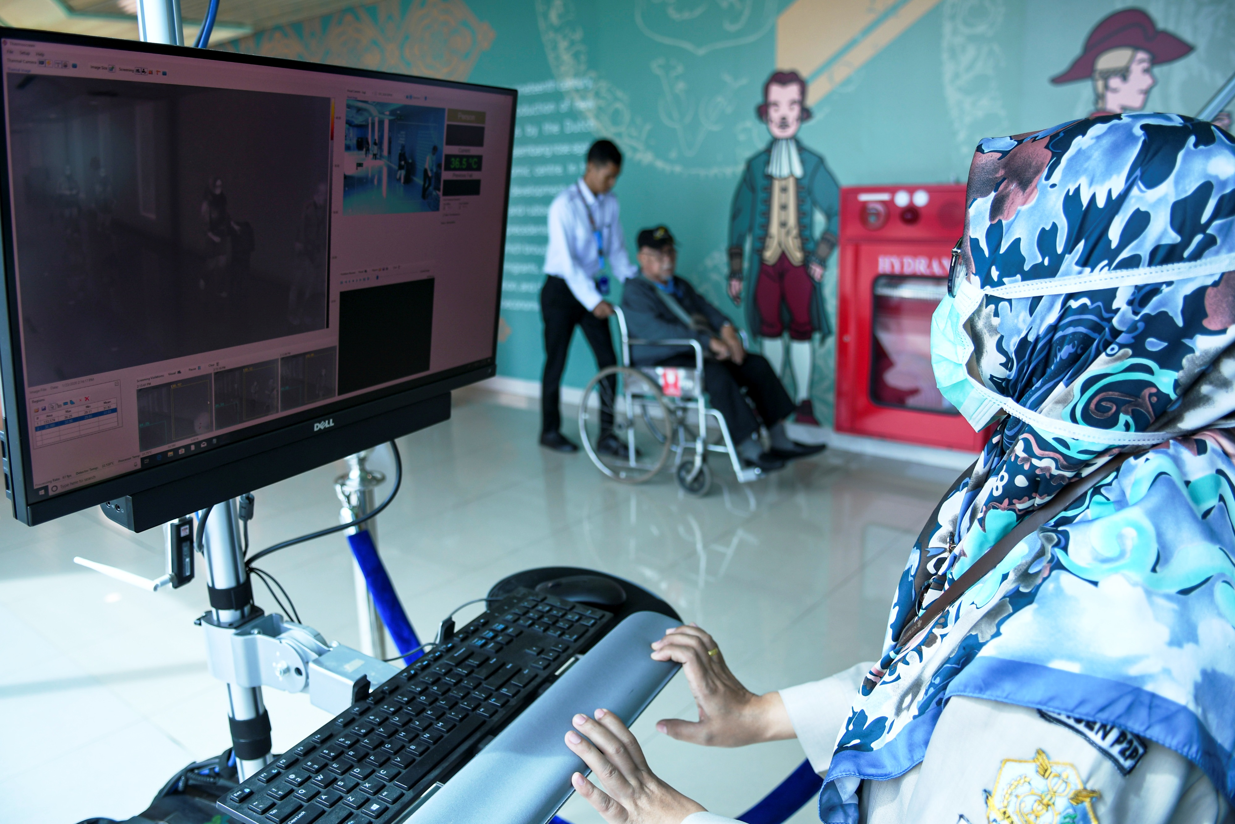 Seorang petugas sedang mengamati monitor thermal scanner di bandara.