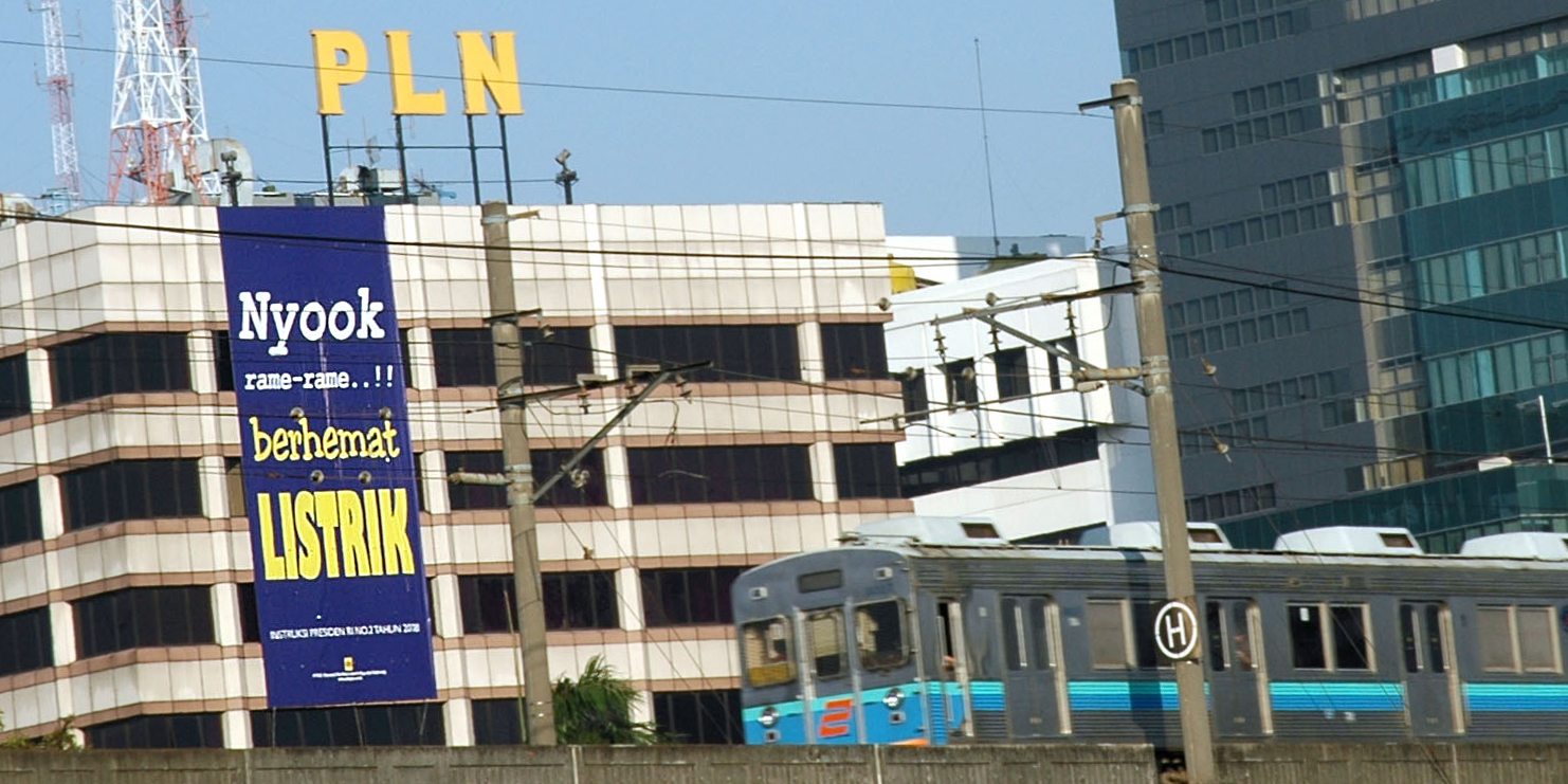 Sebuah kereta melewati spanduk persuasif untuk menghemat energi yang dipasang di kantor pusat Perusahaan Listrik Negara (PLN) di Jakarta.