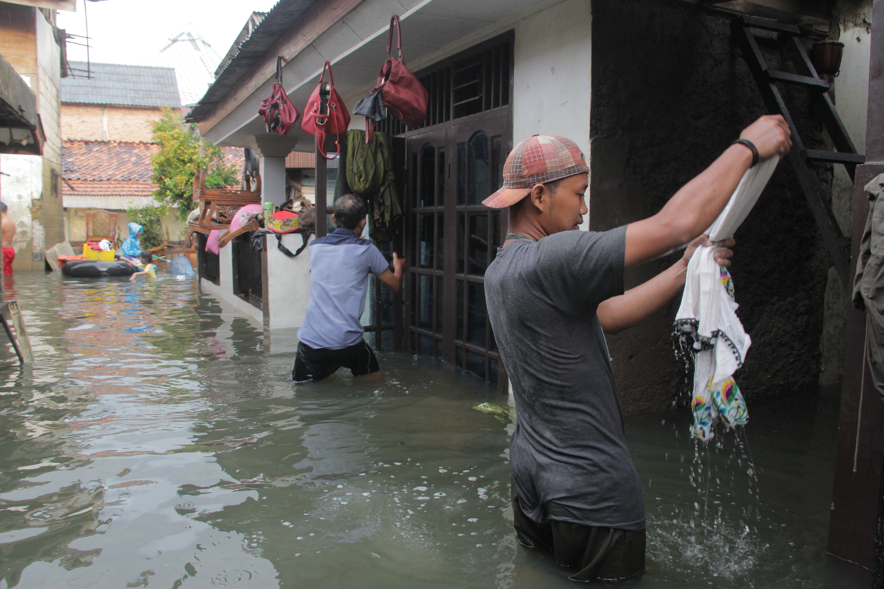 Warga membersihkan barang yang terendam air di kawasan di RT 07 RW 01, Kampung Duri Semanan, Kalideres, Jakarta Barat.