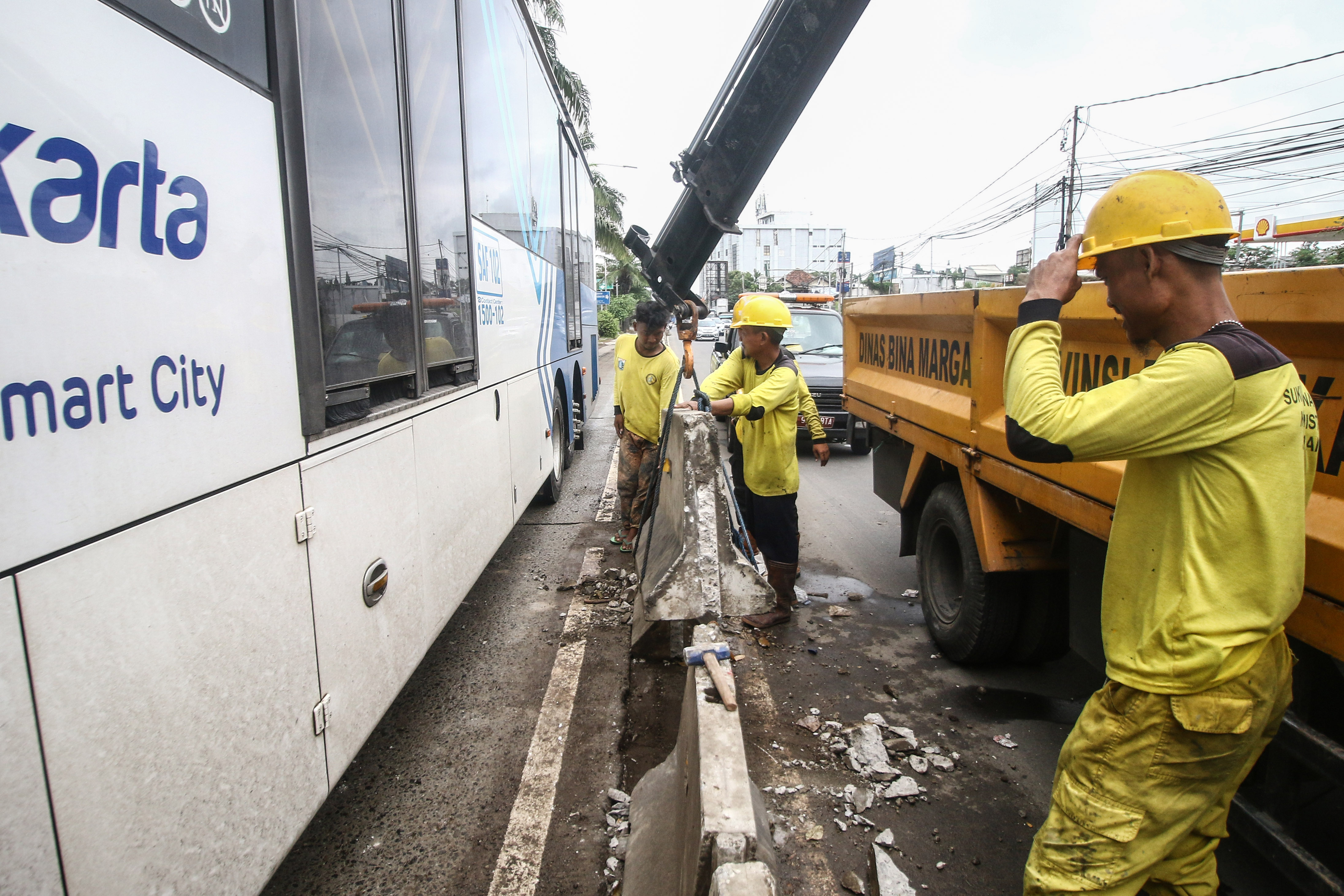 Pascabanjir, petugas memasang beton pembatas jalur Transjakarta di Jalan Daan Mogot, Jakarta.