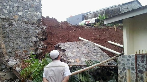 Warega memandangi tebing longsor yang menimpa rumahnya di Kelurahan Cipayung, Depok.
