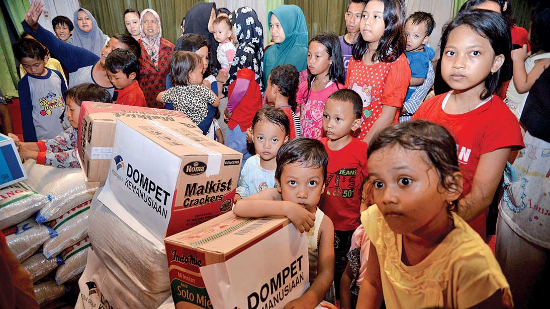 Anak-anak berada di dekat paket bantuan yang diberikan Media Group di Kompleks Wisma Siti Maryam, Kedoya Utara, kemarin. 