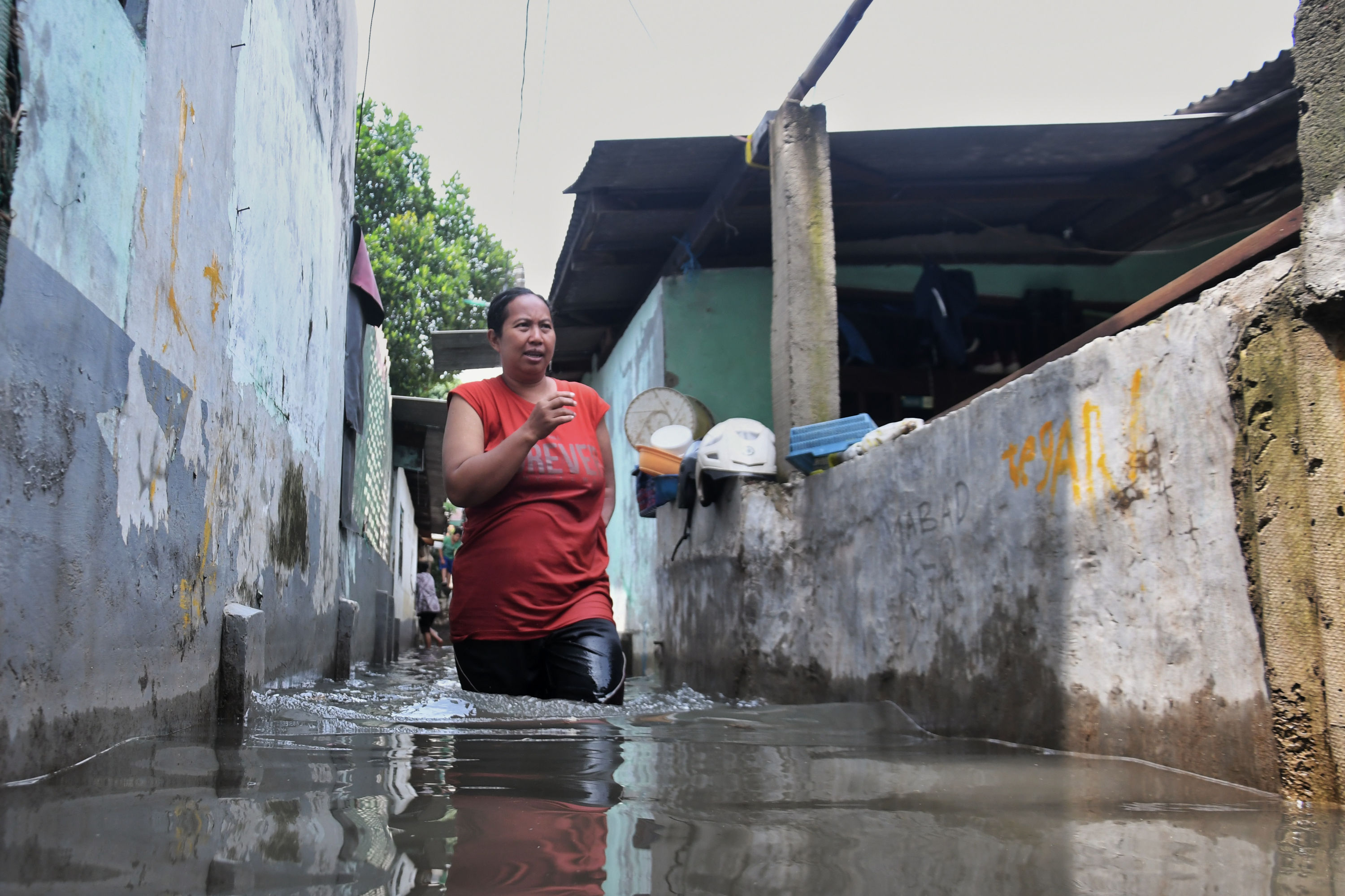 Warga berjalan menembus banjir di kawasan perumahannya di kawasan Kebon Jeruk, Jakarta.
