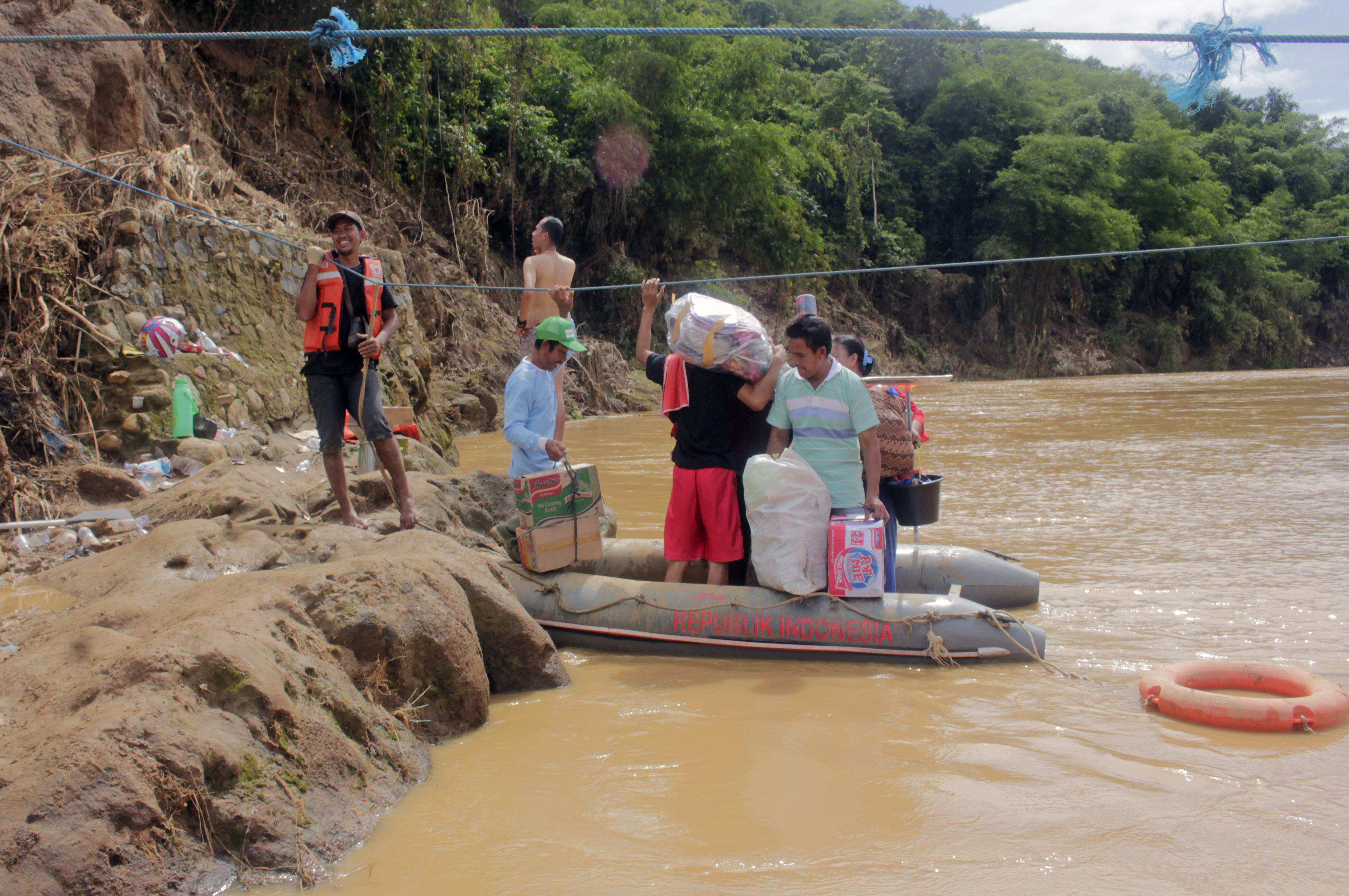  Relawan membantu warga akan menyeberang Sungai Ciberang Lebak dengan perahu karet. Kini warga sedang membangun jembatan darurat di situ. 