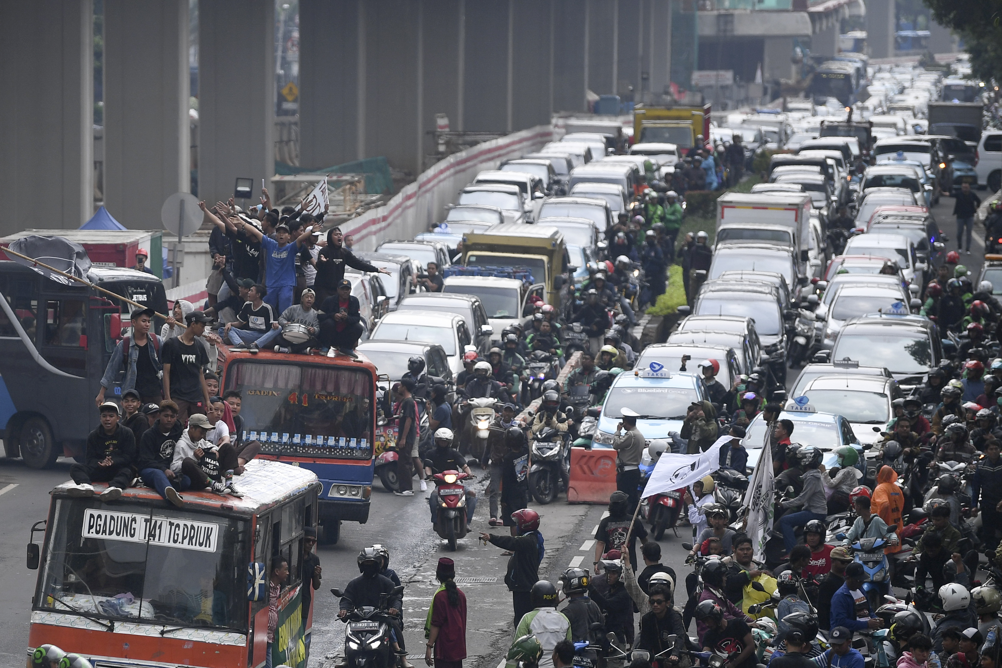 Warga Tanjung Priok menaiki atap metromini saat melakukan aksi di depan gedung Kemenkumham, Jakarta, Rabu (22/1/2020)