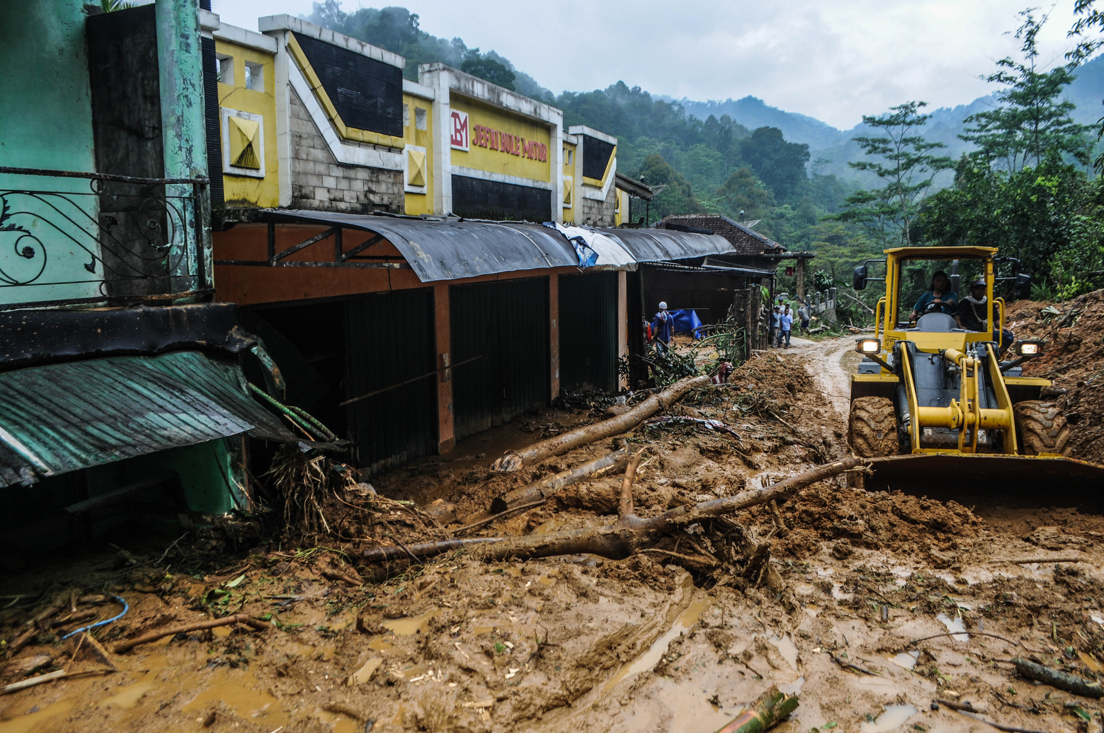 Petugas menggunakan alat berat untuk membersihkan tumpukan lumpur yang terbawa banjir di Desa Ciladaheun, Lebak, Banten, beberapa waktu llau