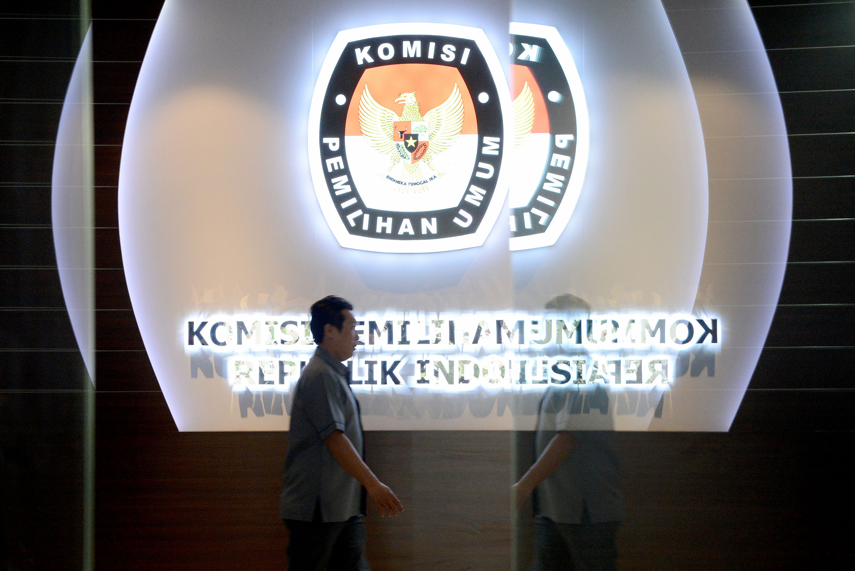 Pegawai Komisi Pemilihan Umum (KPU) melintas di depan logo lembaga di Kantor KPU, Imam Bonjol, Jakarta Pusat