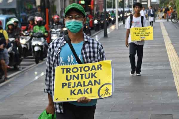 Sejumlah aktivis Koalisi Pejalan Kaki membawa poster kampanye dalam rangka Hari Pejalan Kaki Nasional.