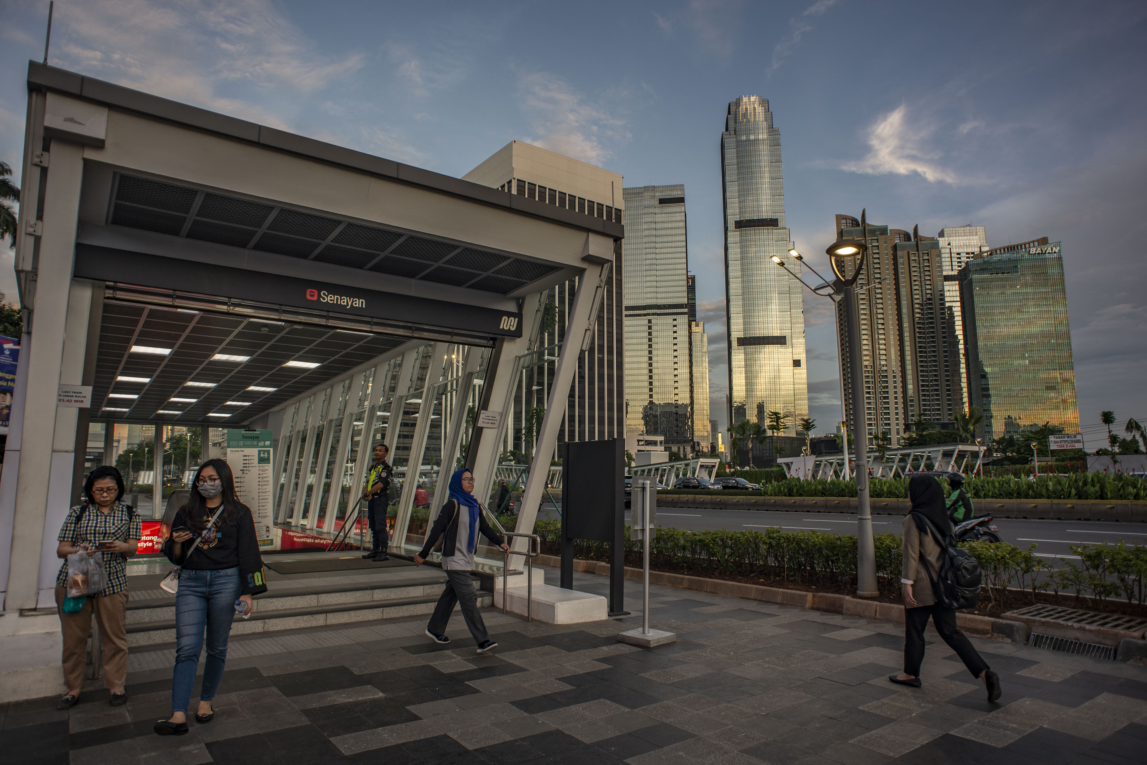 Warga berjalan dengan latar belakang gedung bertingkat di kawasan Jalan Jendral Sudirman, Jakarta, Senin (27/1/2020).
