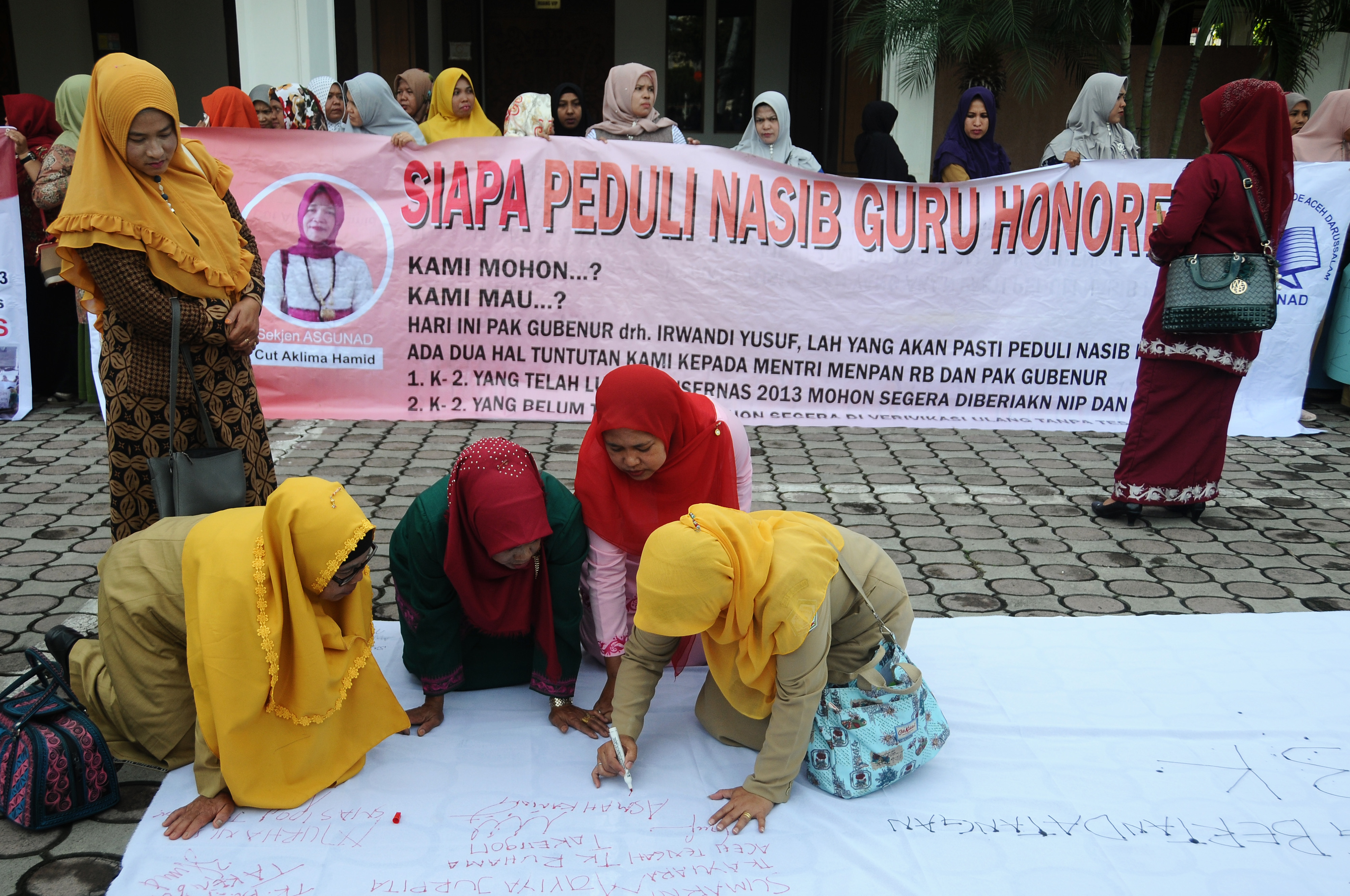 Sejumlah guru honorer Kategori 2 (K2) membubuhkan tanda tangan pada spanduk saat menggelar aksi damai di gedung DPRA, Banda Aceh
