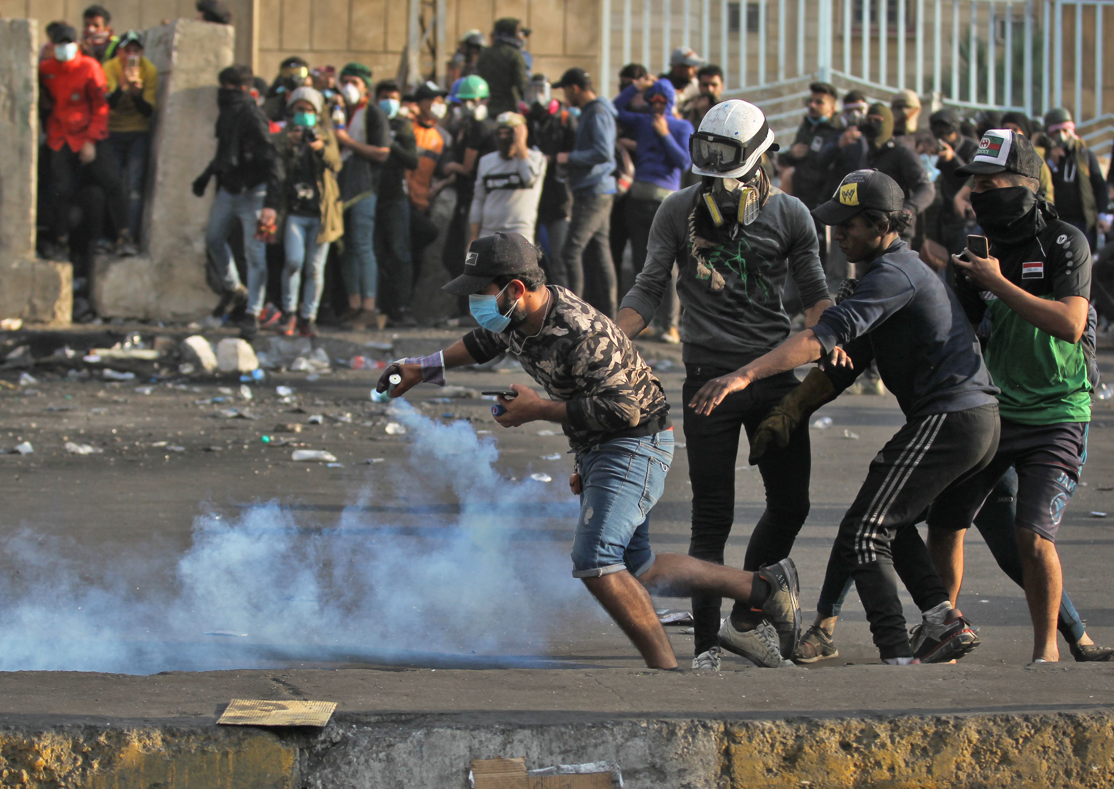 Seorang demonstran mengambil tabung gas air mata yang ditembakkan polisi dalam kasi demonstrasi di Baghdad, Irak.