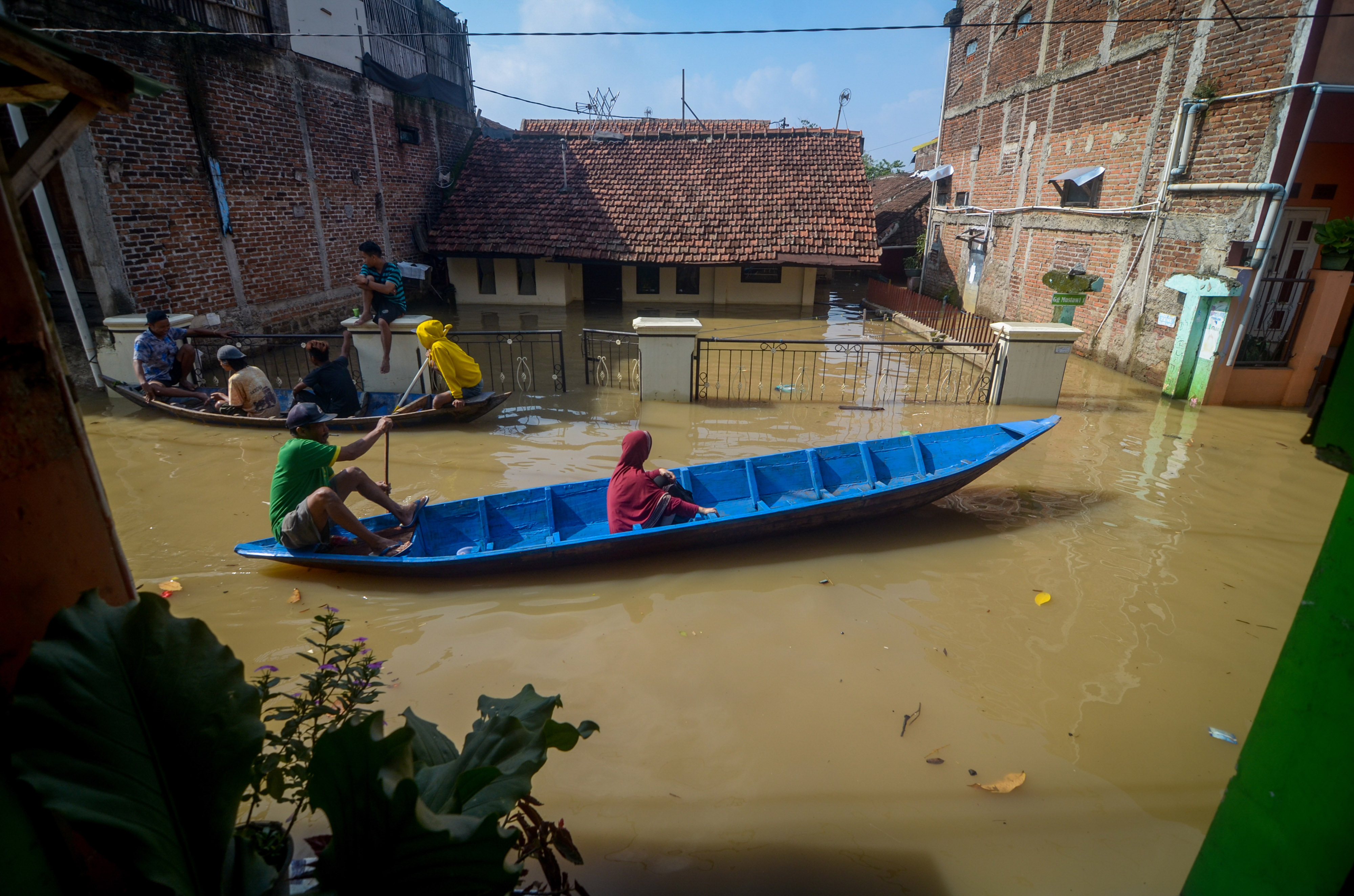 Warga melintasi banjir menggunakan perahu yang melanda Kampung Bojongasih, Dayeuhkolot, Kabupaten Bandung, Jawa Barat.