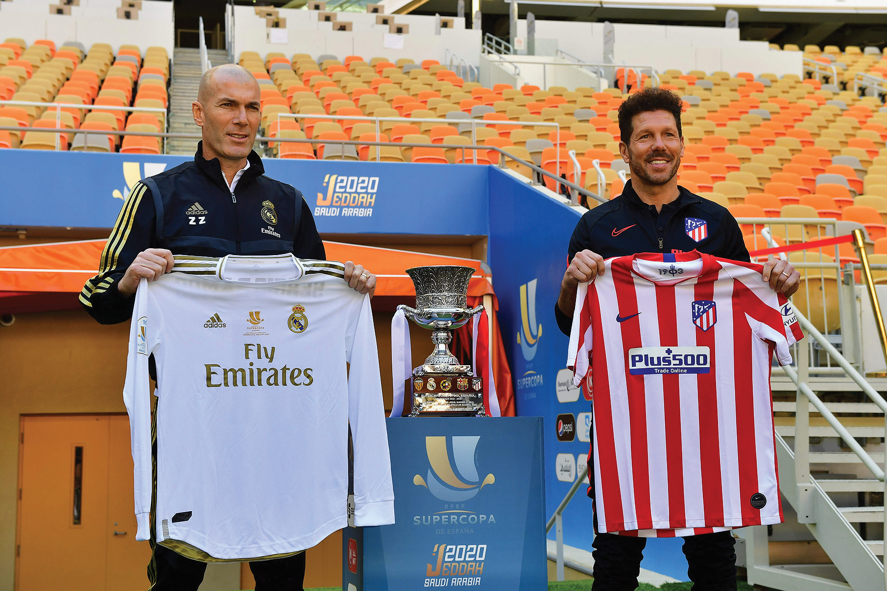 Pelatih Real Madrid Zinedine Zidane (kiri) dan pelatih Atletico Madrid Diego Simeone berpose sambil memegang kostum tim asuhannya kemarin.