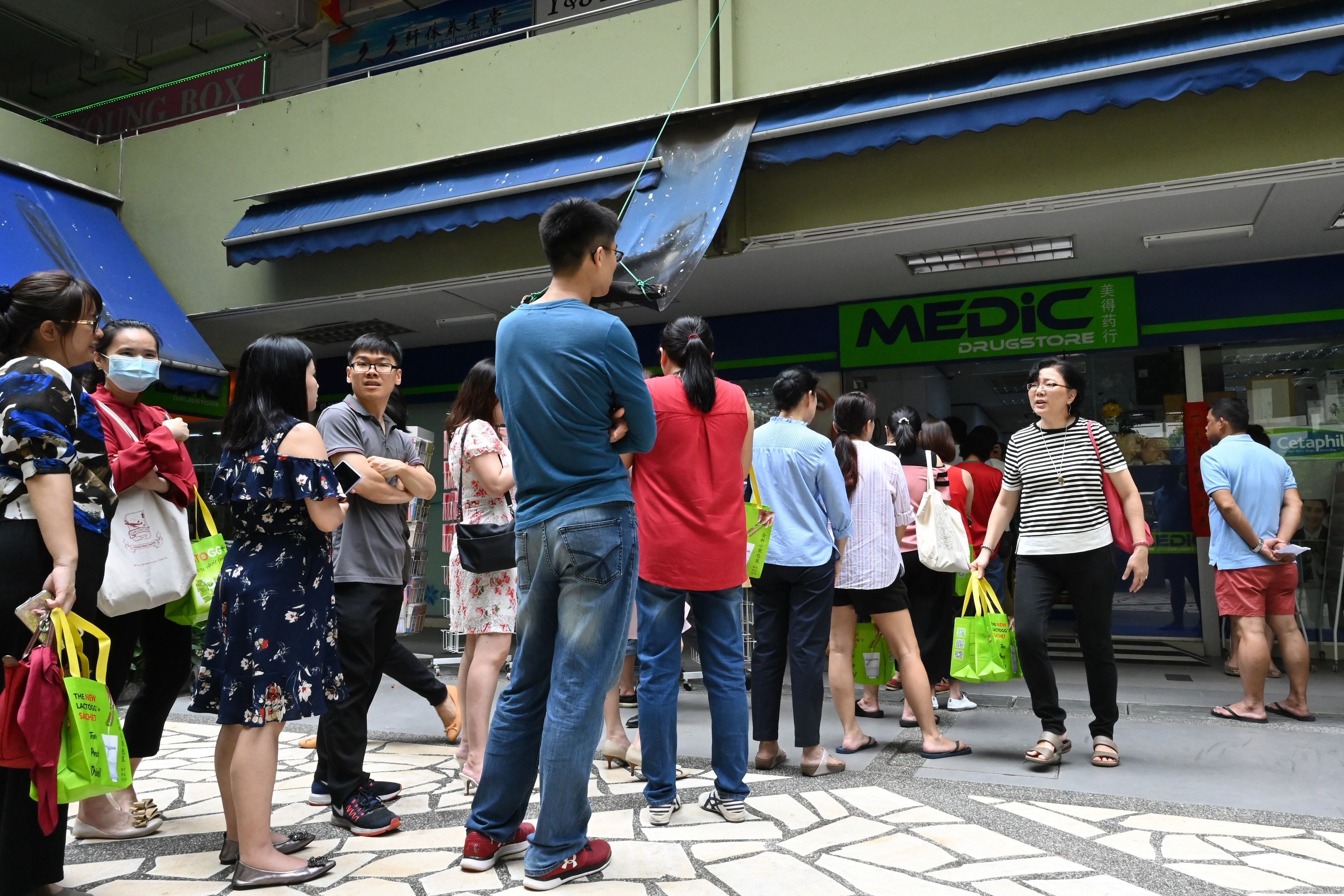 Warga Singapura mengantre di luar toko farmasi untuk membeli masker pelindung, termometer dan cairan pembersih tangan.