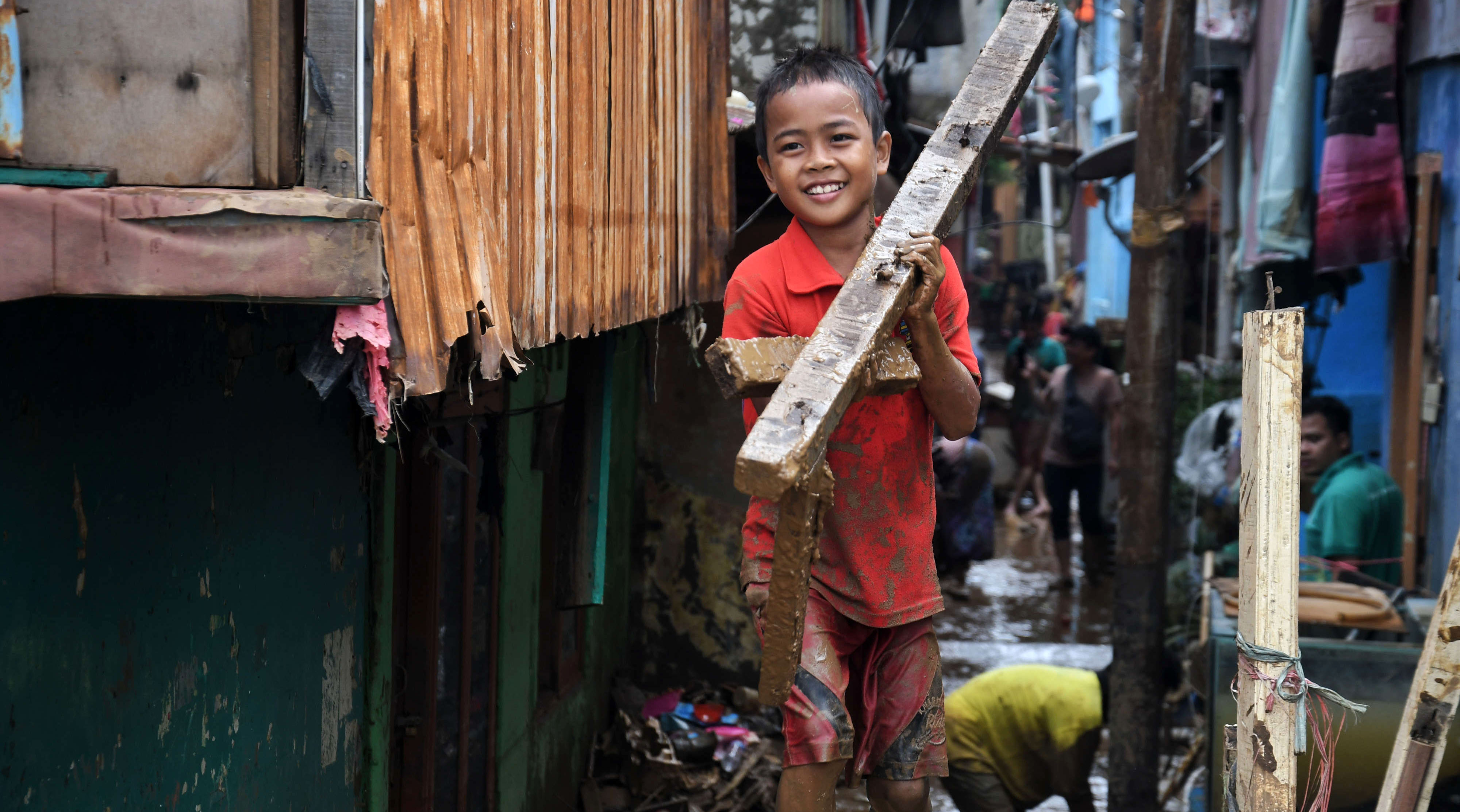 membersihkan rumahnya dari sampah dan lumpur akibat banjir di kawasan Kampung Pulo, Kampung Melayu.