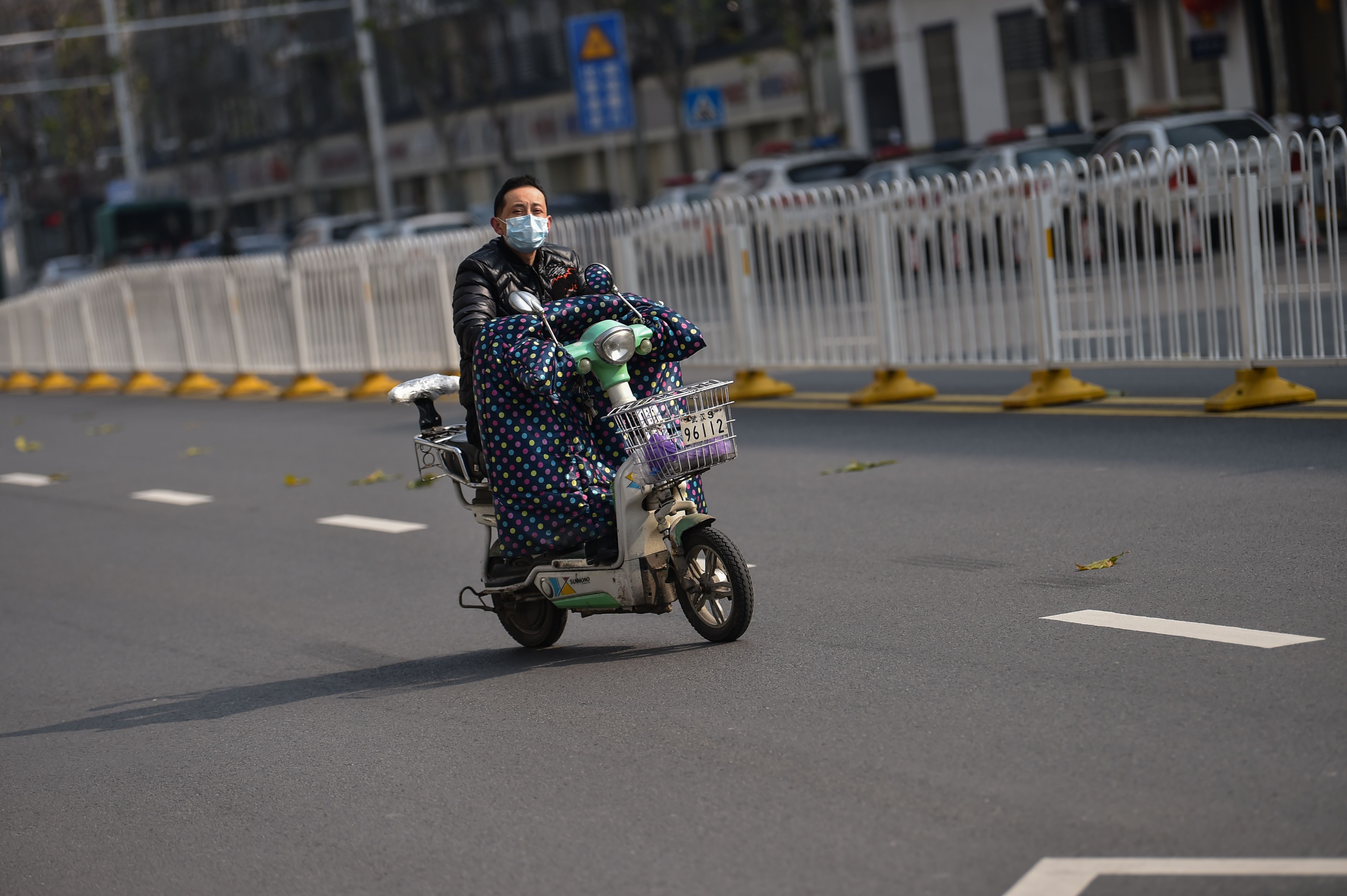 Seorang pria dengan perlindunganwajah tampak mengendarai sepeda motor di Wuhan yang kini bak kota mati.