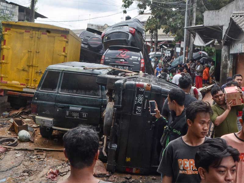 Sejumlah warga berjalan di dekat mobil yang rusak pascabanjir di Perumahan Pondok Gede Permai Bekasi, Jawa Barat.