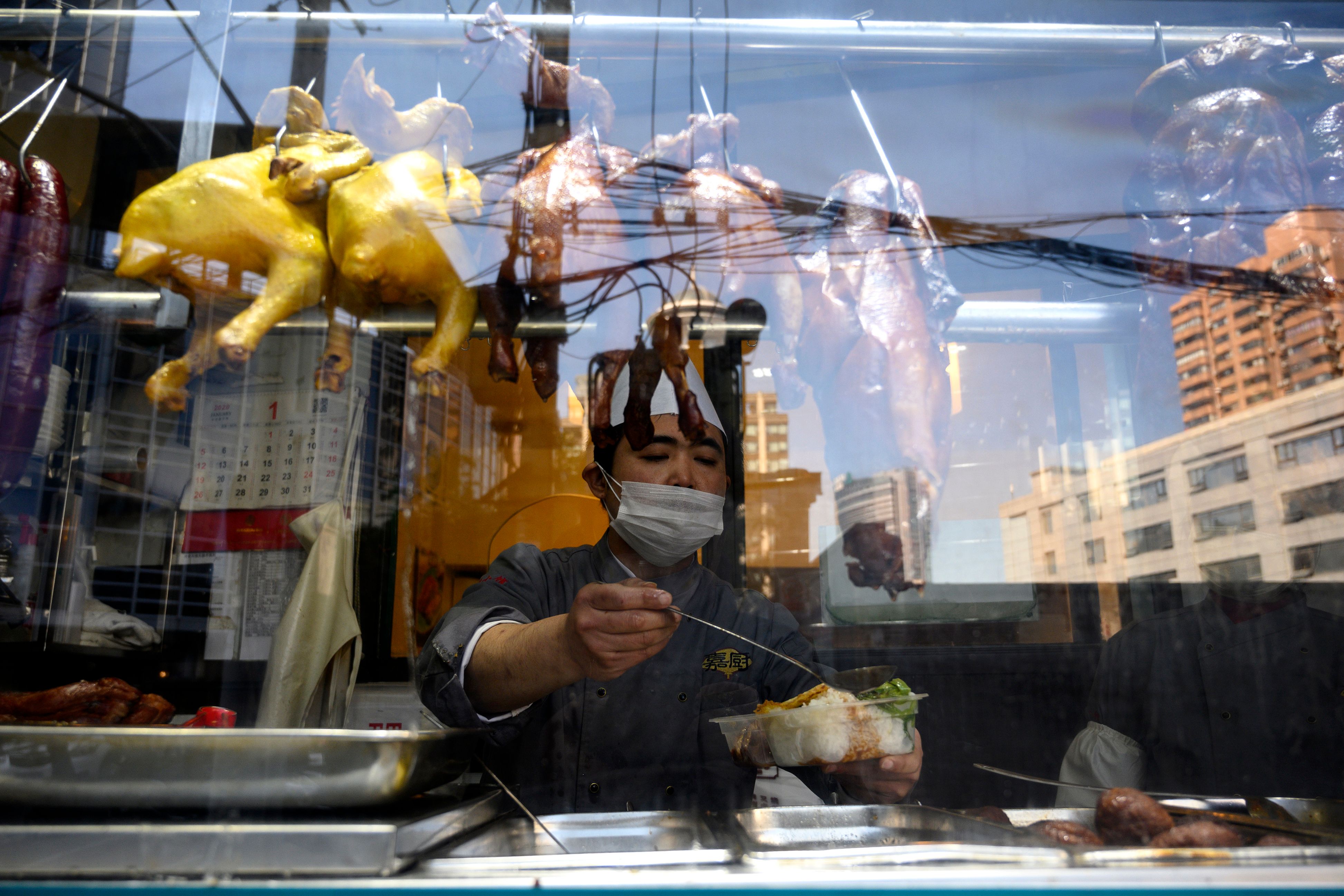 Seorang koki mengenakan masker saat menyiapkan makanan di sebuah restoran di Shanghai, Tiongkok