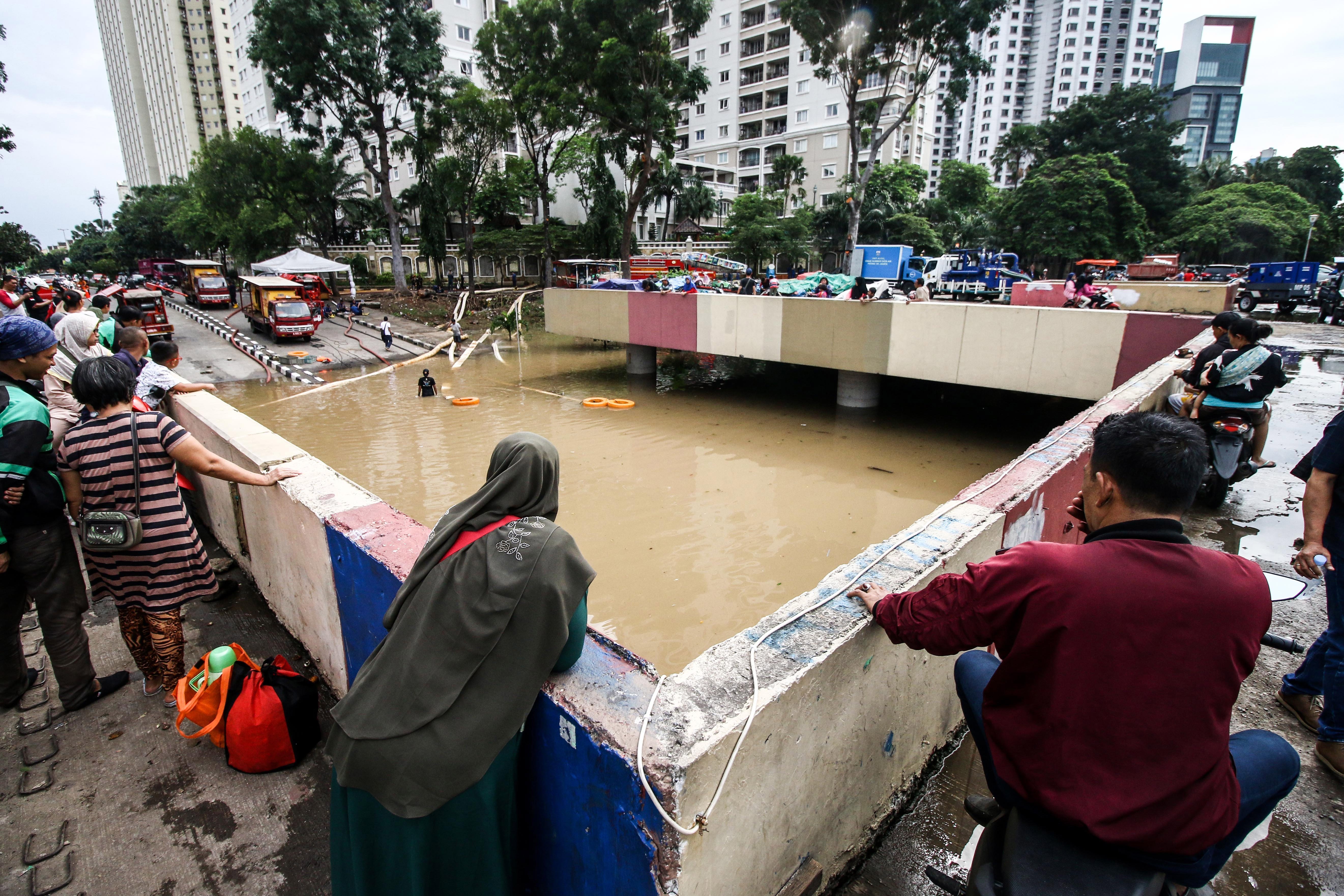 Warga melihat banjir yang menutup Underpass Kemayoran, Jakarta, Minggu (2/2/2020). 