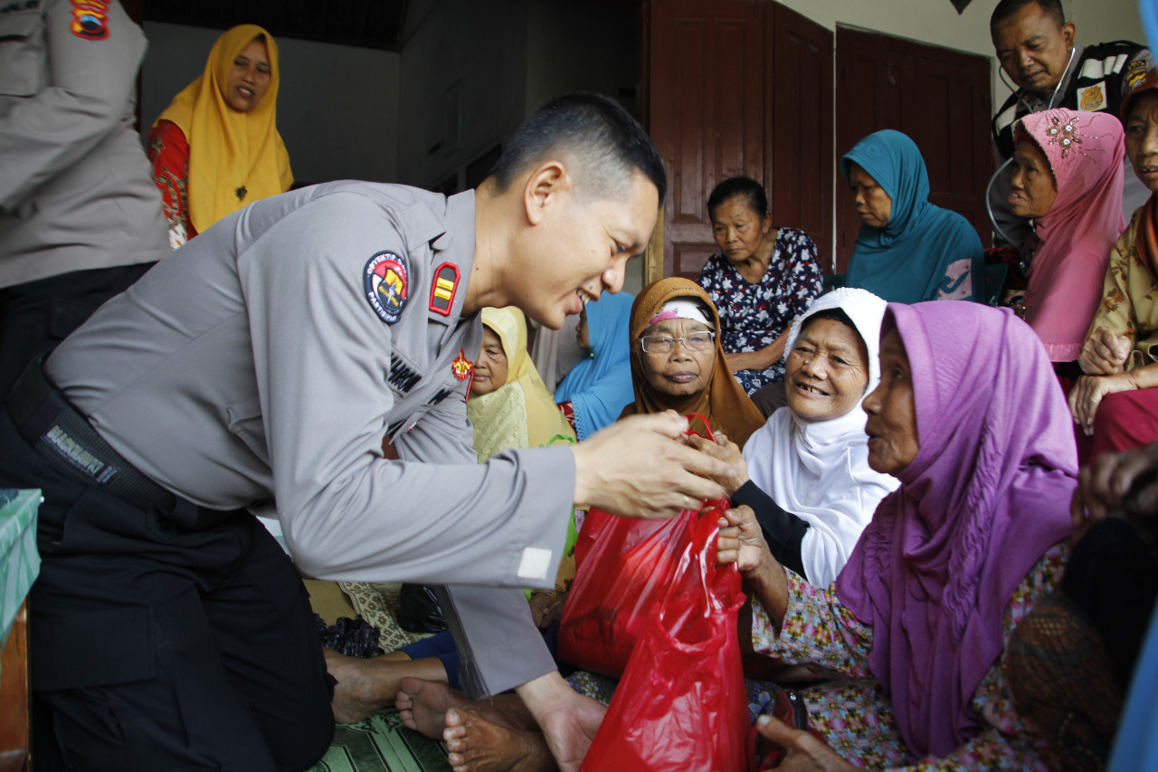 Kasubag Humas Polres Klaten, Iptu Nahrowi, menyerahkan paket sembako kepada warga kurang mampu pada kegiatan baksos Jumat Berkah. 