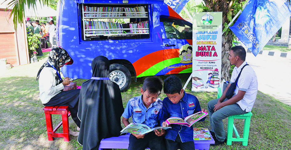 Siswa sekolah Sukma Bangsa membaca buku di perpustakaan mobil yang tersedia dalam pameran Kenduri Kebangsaan di Sekolah Sukma Bangsa Bireun.