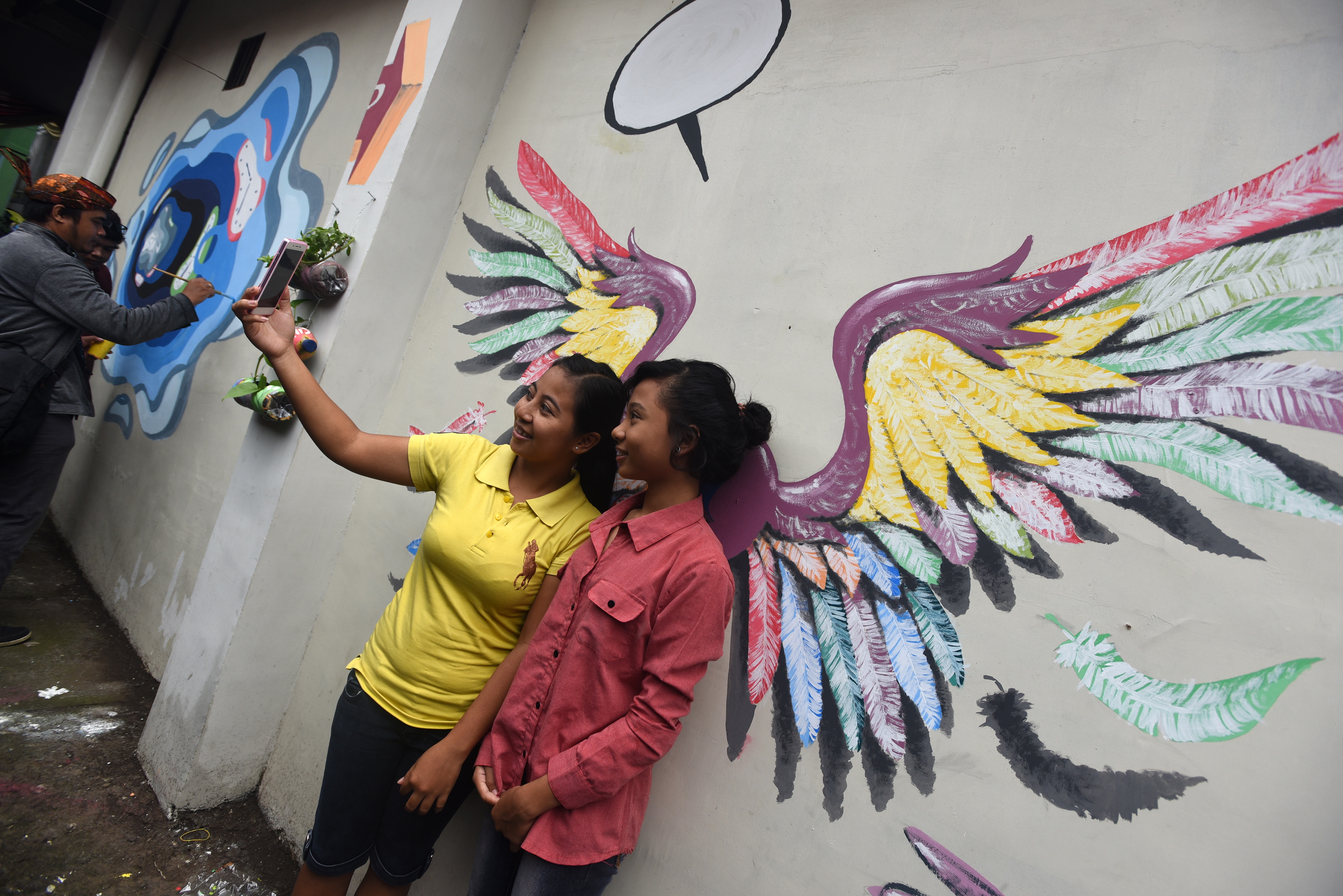 Warga berfoto dengan latar mural di Gang Dolly, Surabaya, Jawa Timur, yang berubah menjadi kampung wisata.
