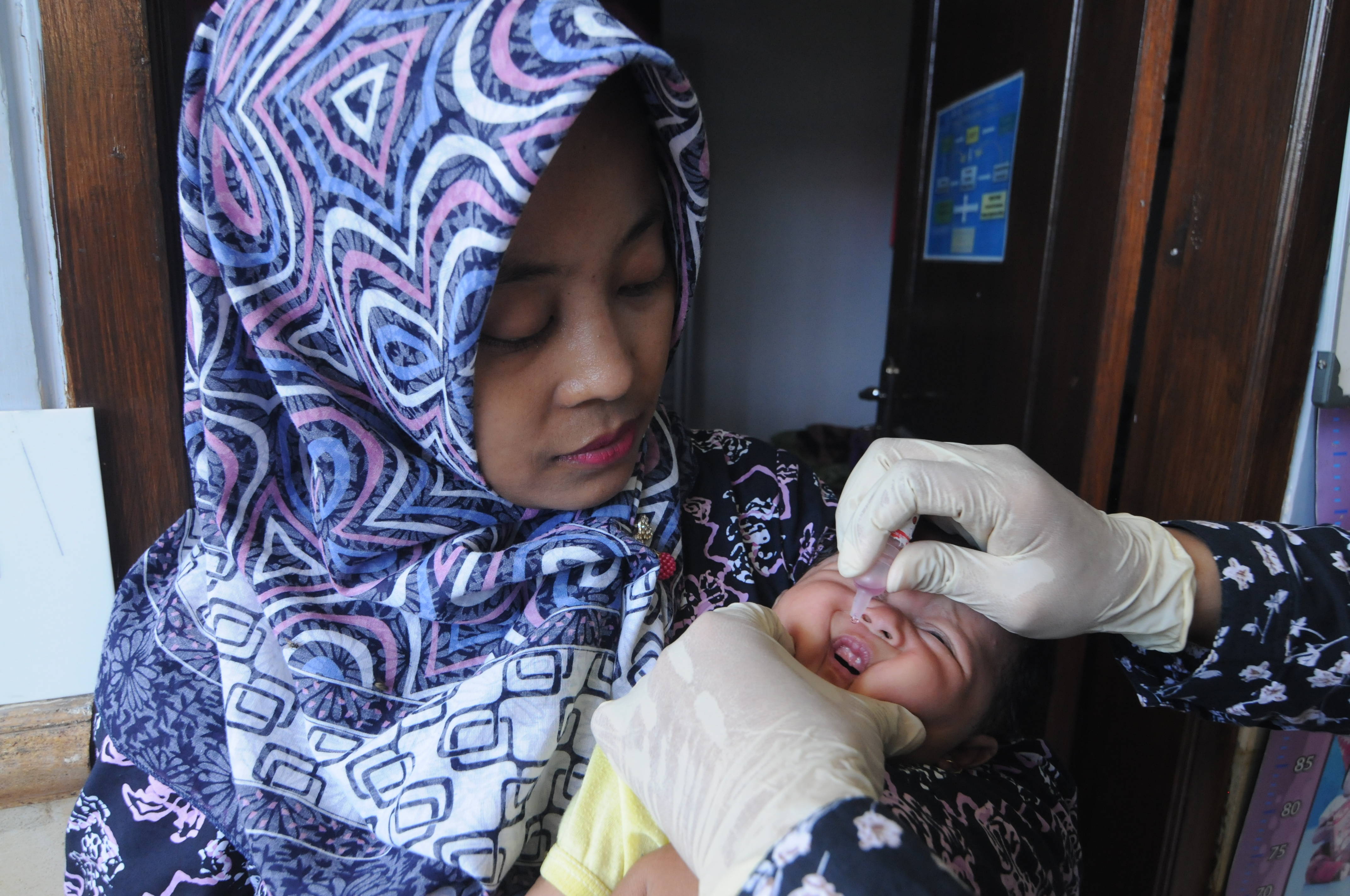 Bidan (kanan) memberikan imunisasi polio pada bayi usia dua bulan di Pamekasan, Jawa Timur.