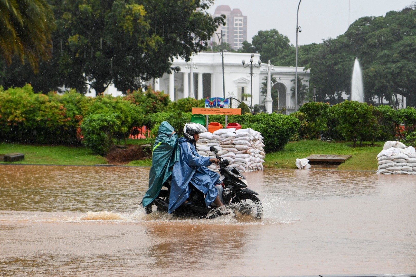  Pengendara sepeda motor melintasi banjir di Jalan Medan Merdeka Barat, Jakarta, Minggu (2/2/2020).